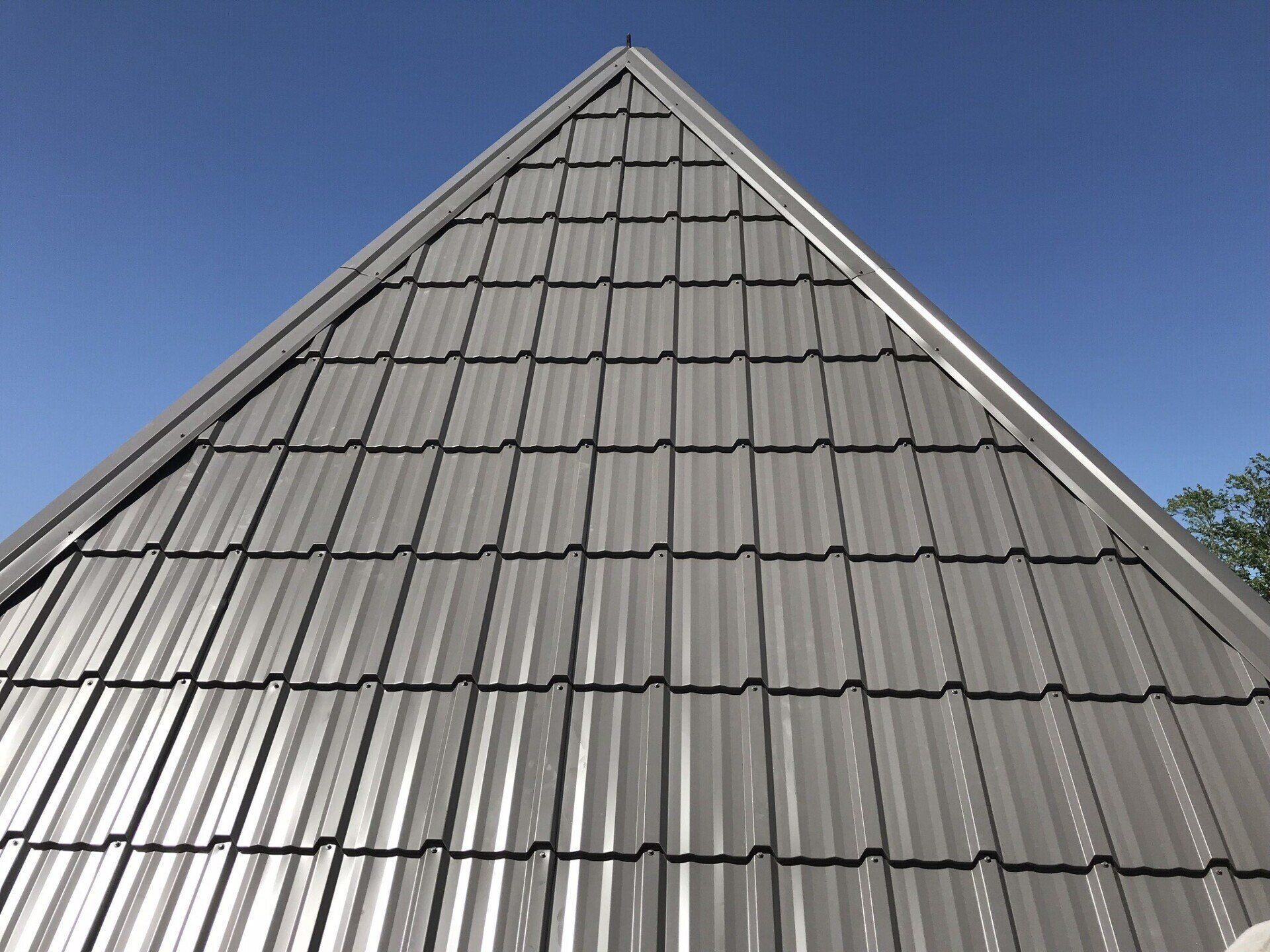 Gray metal tile roof against a clear blue sky.