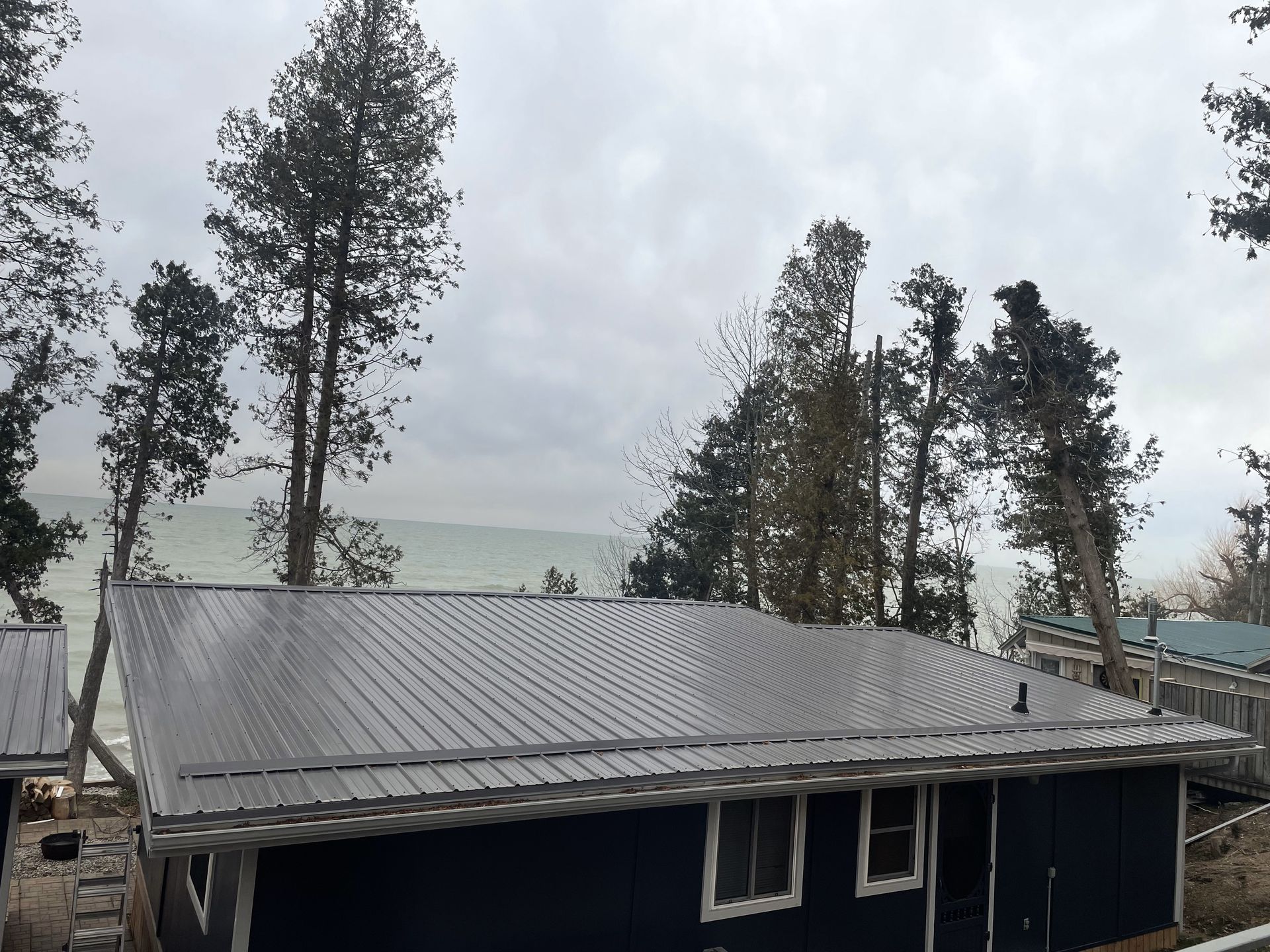 A blue house with a metal roof and a view of the ocean