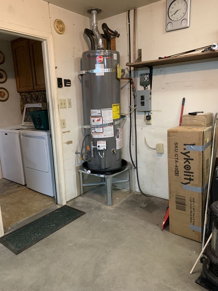 Basement utility room with a tall gray water heater, laundry area, and cardboard boxes.