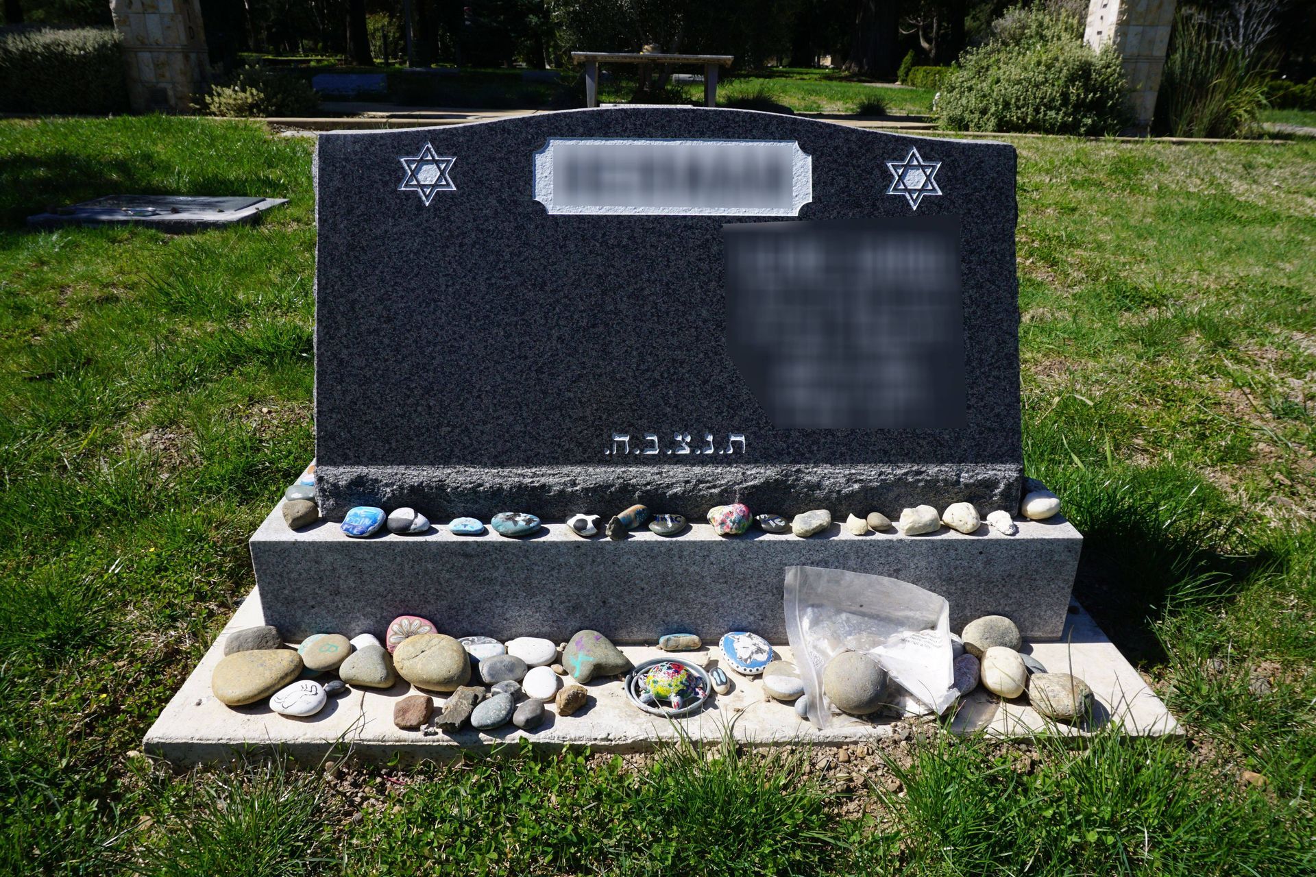 A grave with flowers and a gravestone with a rose on it.