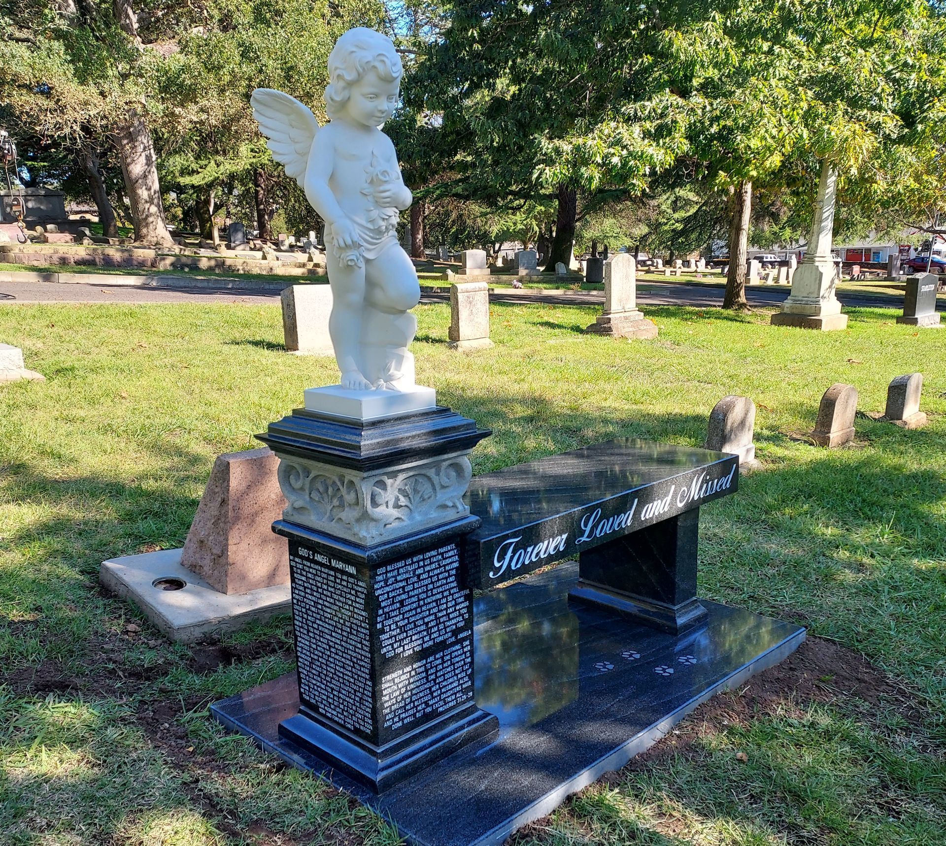 A gravestone with a cross on it is in the middle of a grassy field.