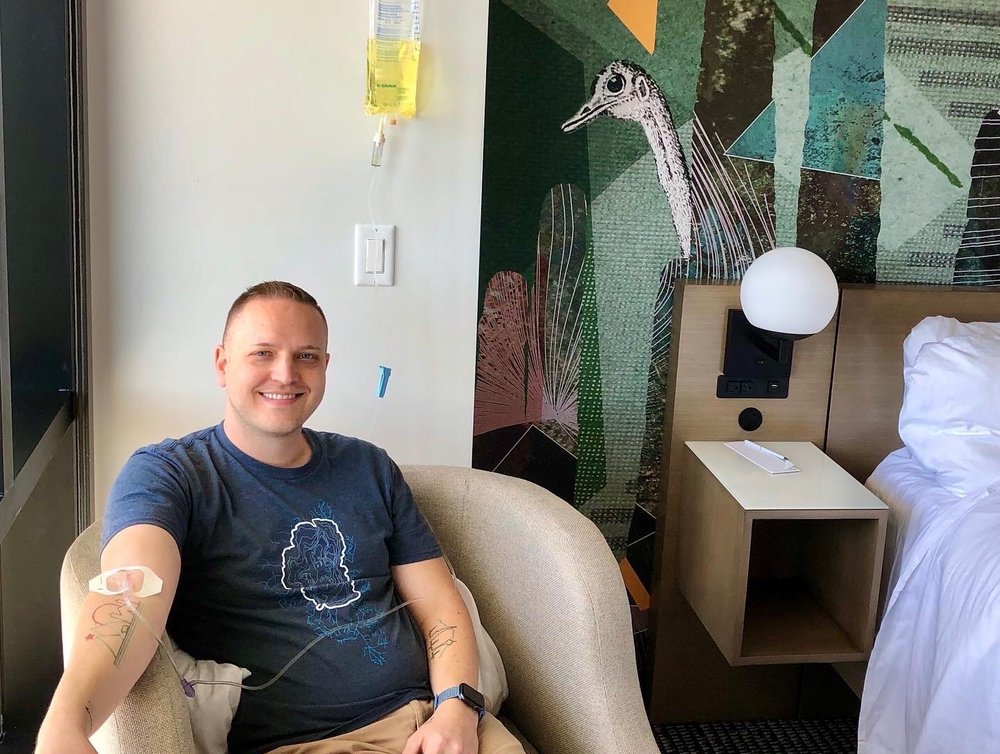 A man is sitting in a chair with a drip on his arm.