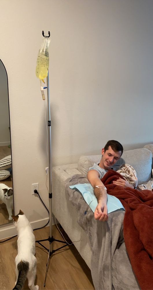 A man is laying on a couch with an iv in his arm.