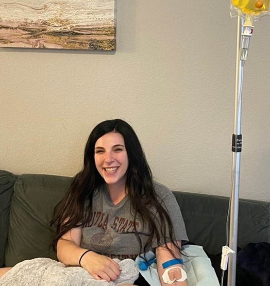 A woman is sitting on a couch wearing a santa state shirt