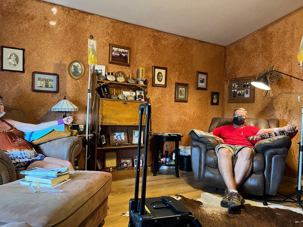 A man is sitting in a chair in a living room while a woman sits on a couch.