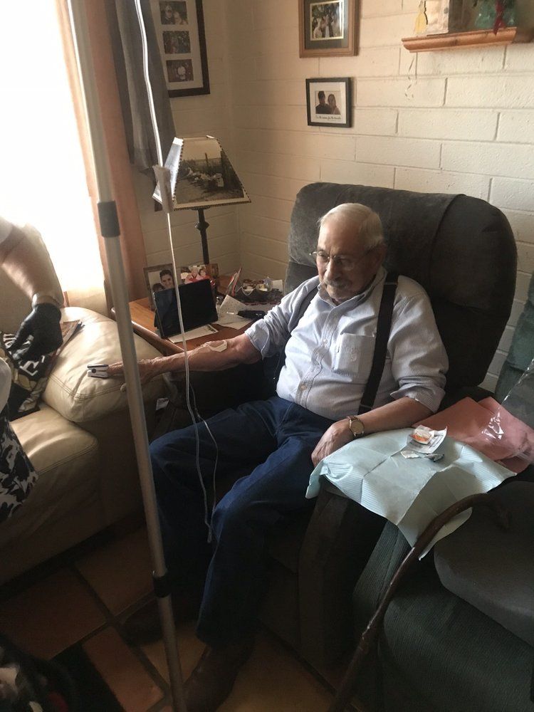 An elderly man is sitting in a chair with an iv in his arm.
