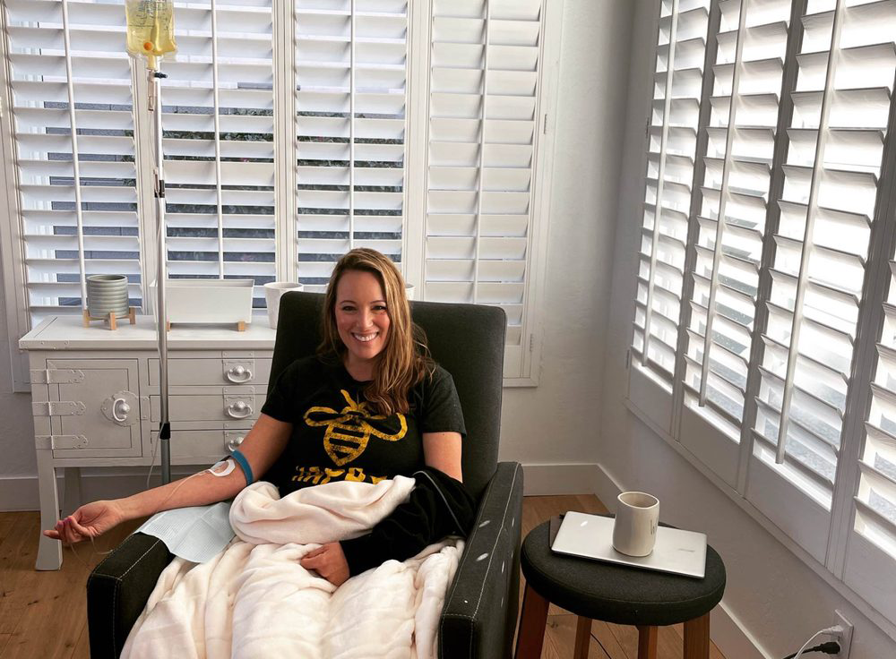 A woman is sitting in a chair with an iv in her arm.