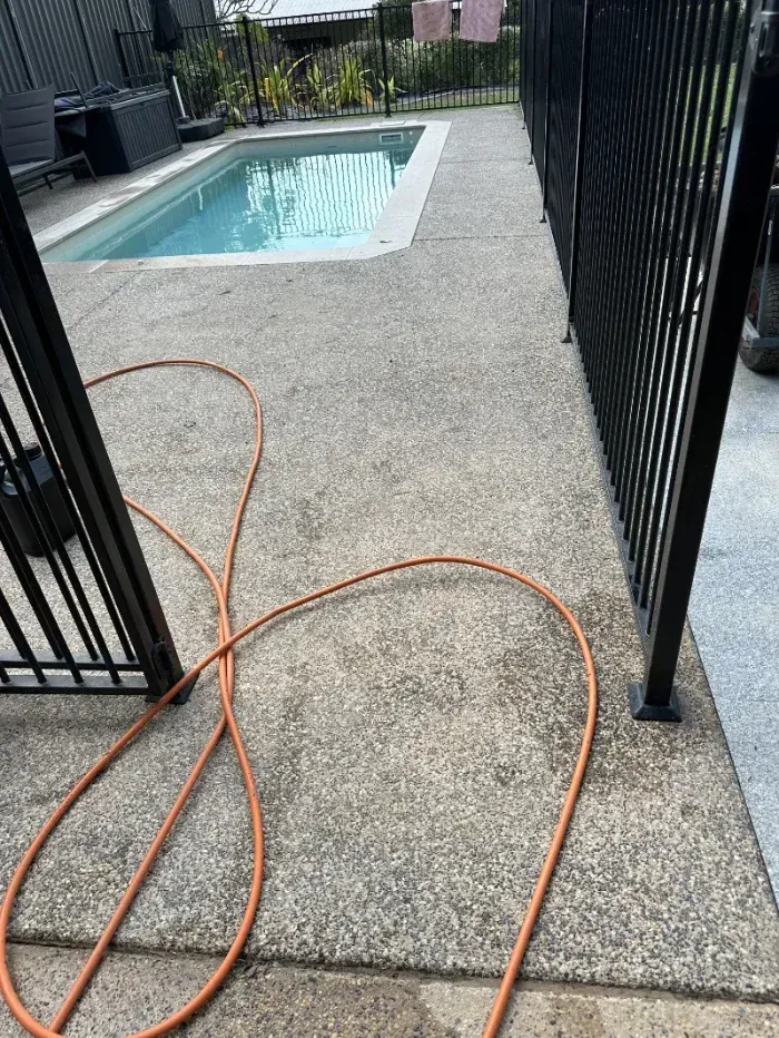 Orange Garden Hose Coils Across a Textured Concrete Patio— I Do It All in Nambour, QLD