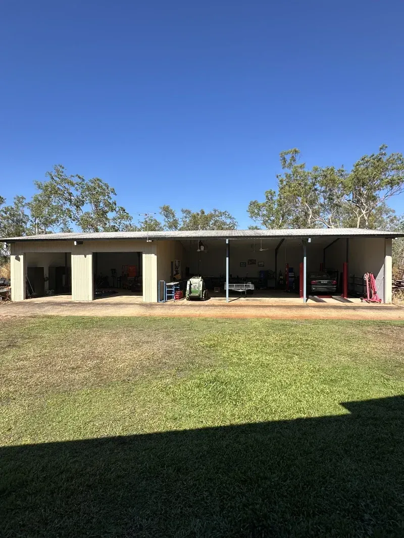 A Wide, Beige Metal Shed with Open Bays Sits on A Patch of Grass — I Do It All in Caloundra, QLD