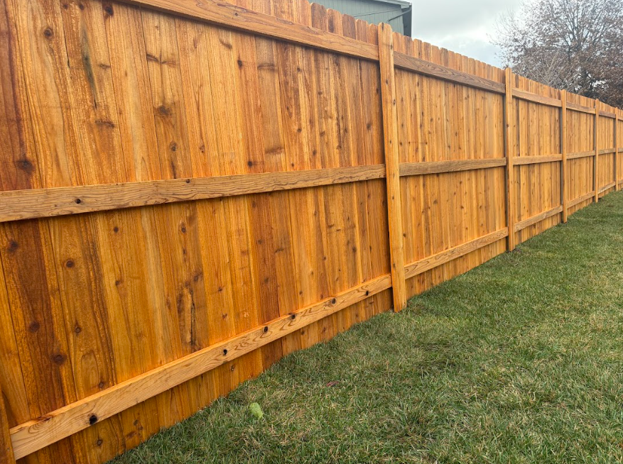 New wooden privacy fence along a grassy yard under an overcast sky