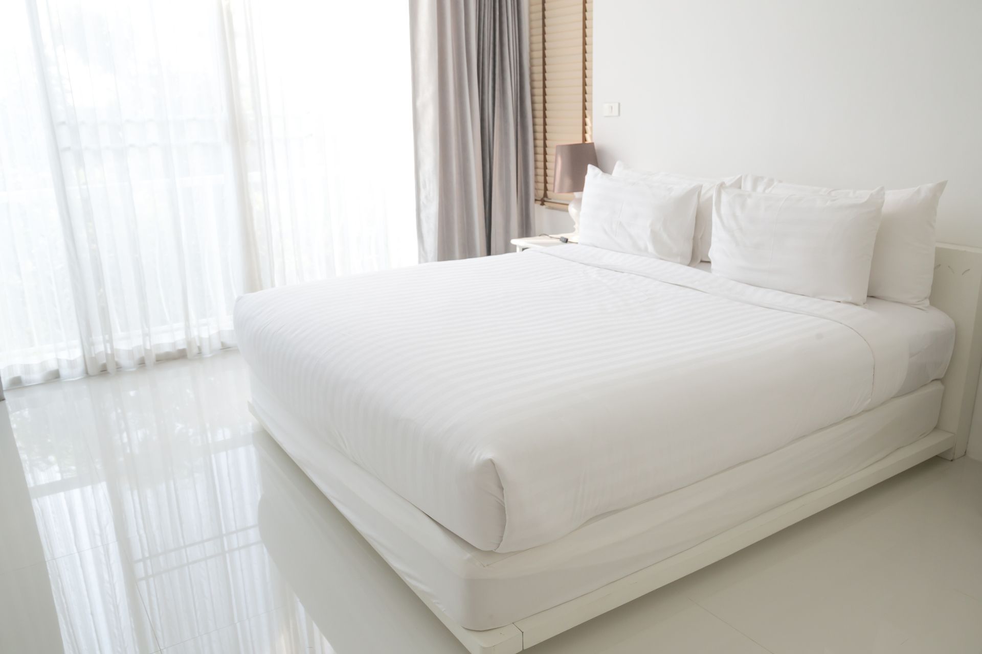 Una cama con sábanas blancas y almohadas en una habitación de hotel.