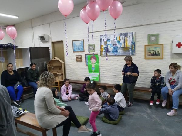 Niños y adultos se reunieron en una sala decorada, con globos rosas y una actividad en círculo en marcha.