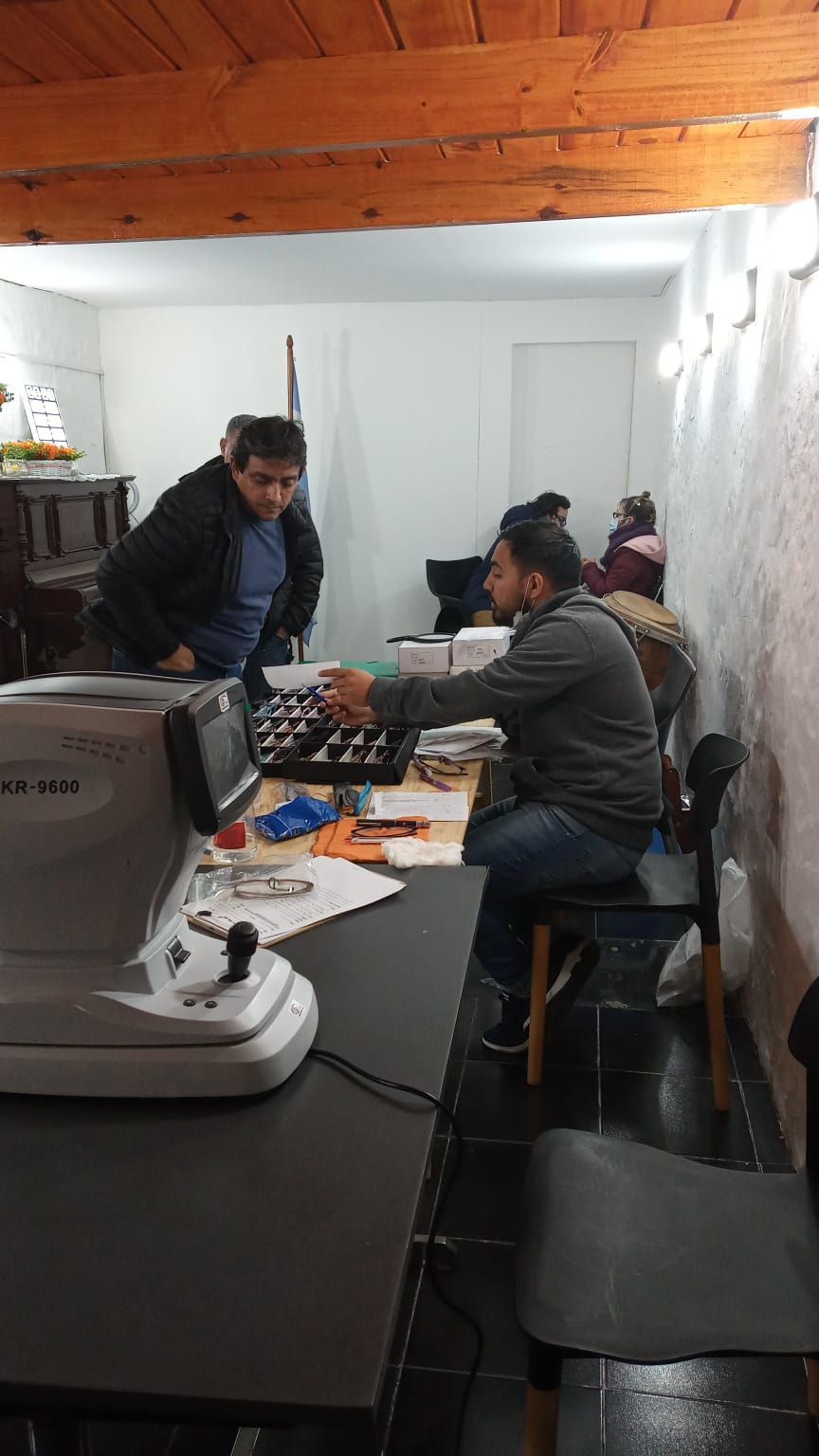 Tres personas jugando al ajedrez en una mesa en una habitación estrecha con techo de madera.