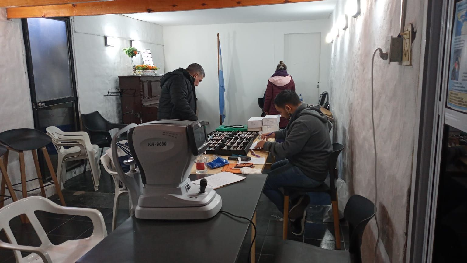 En una pequeña habitación, varias personas se reunieron alrededor de una mesa para jugar a un juego de mesa bajo una luz cálida.