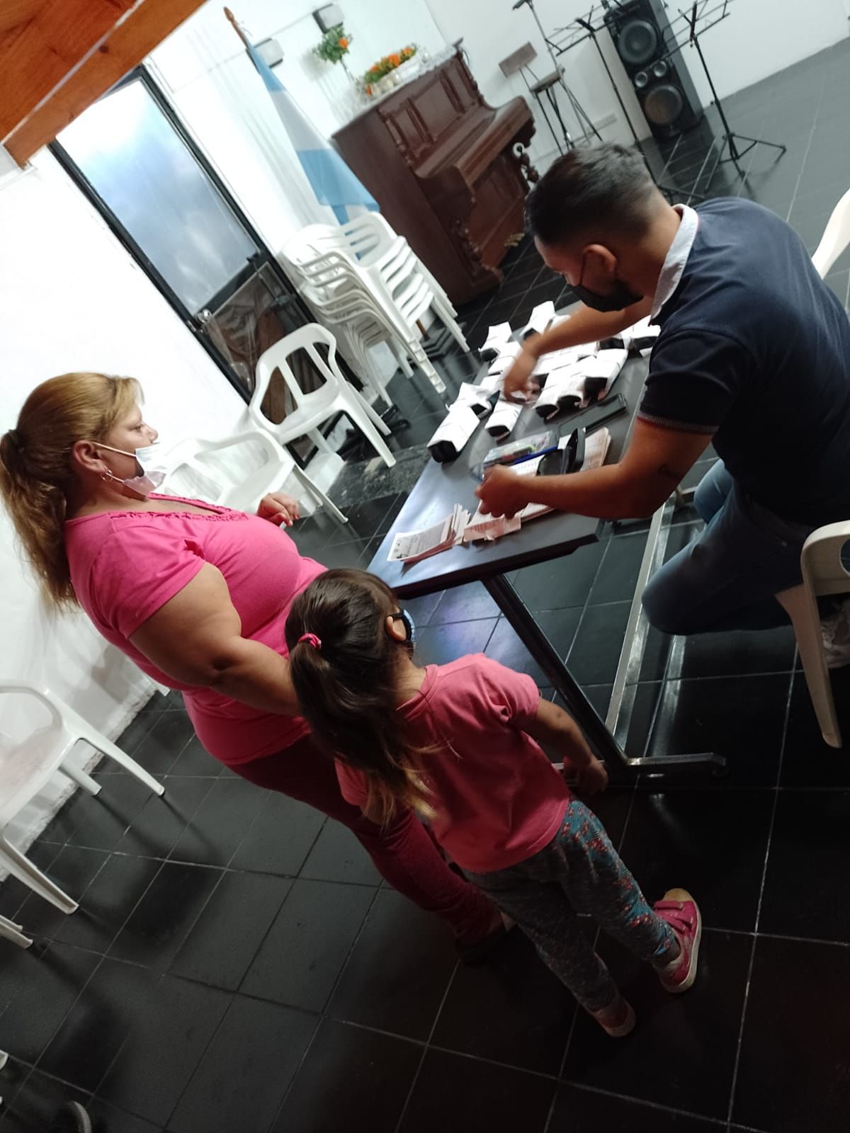 Tres personas sentadas a una mesa mirando papeles en una habitación interior luminosa.
