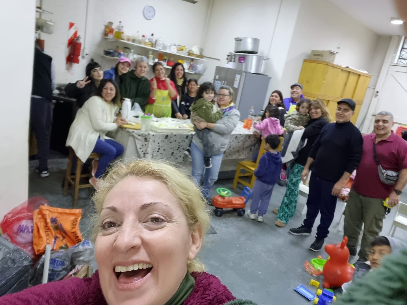 Un grupo sonriente se reunió en una habitación decorada, con una mujer tomándose una selfie en primer plano.