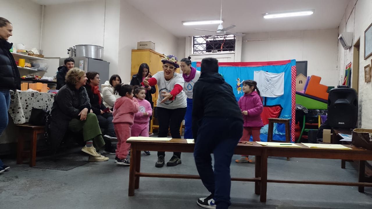 El grupo se reunió en una sala con mesas y conversaron frente a un panel informativo azul y rojo.