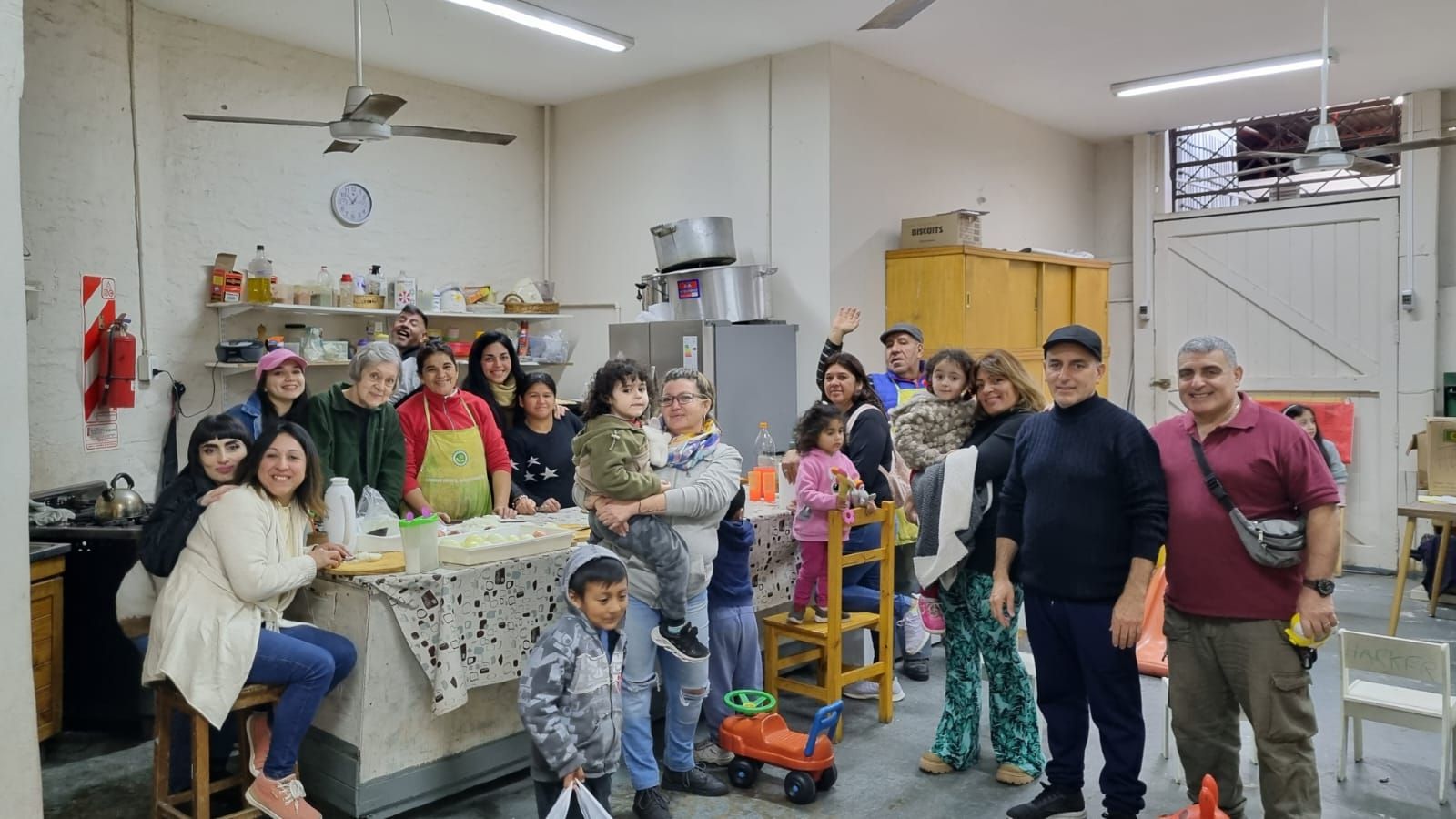 Grupo de personas posando en una habitación bien iluminada con estanterías, mesas y juguetes, sonriendo para una foto grupal.