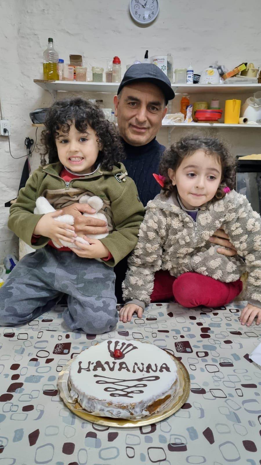 Tres personas sentadas a una mesa con un pastel que dice 