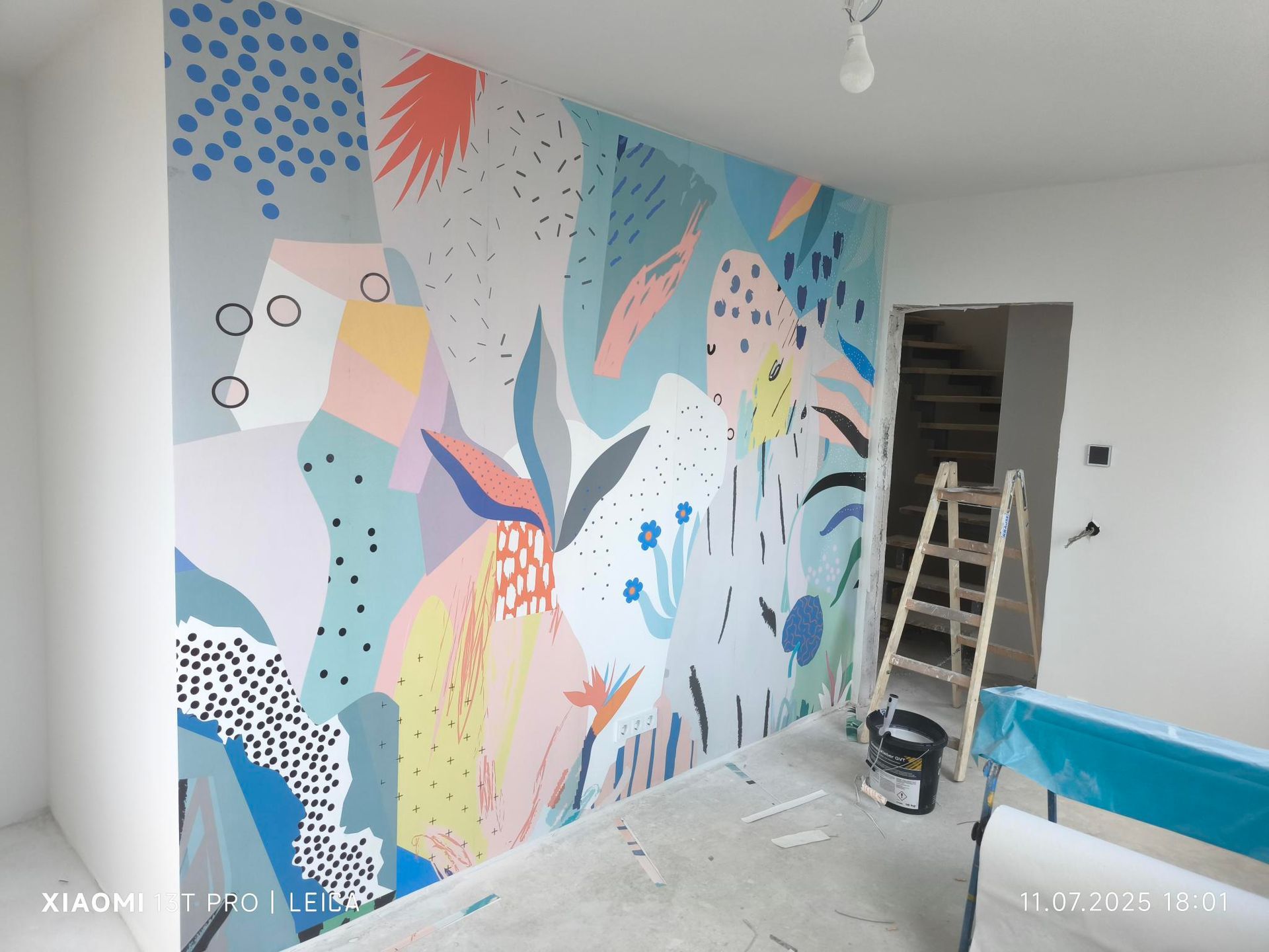 Ein Raum mit einer Leiter und einer bunten Wand.