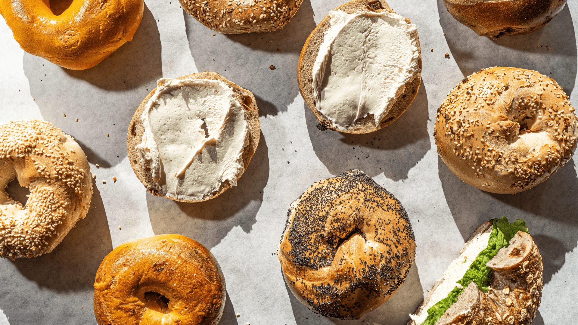 Freshly baked Polish bagels on a wooden board with sesame seeds and herbs