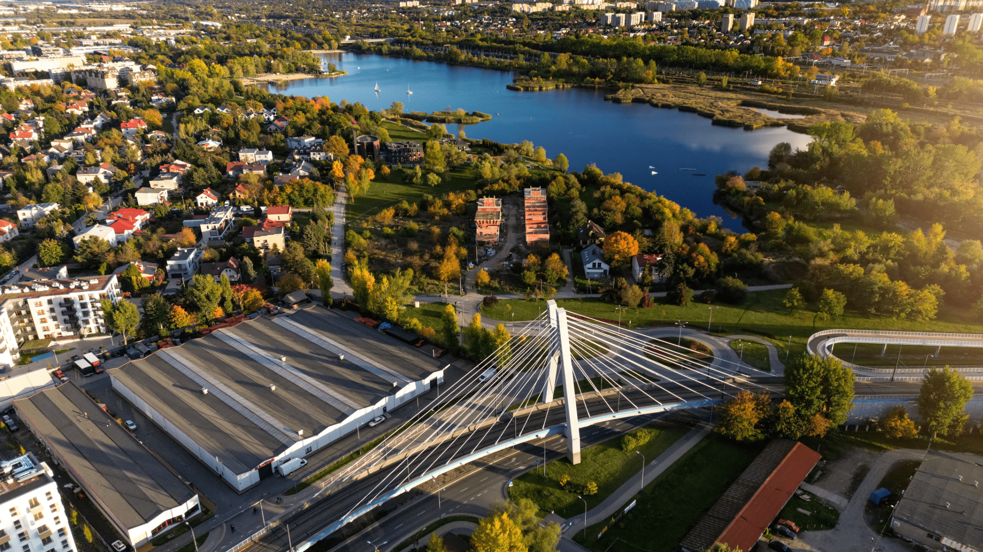 Large artificial lake with surrounding greenery and people enjoying water activities in Kraków