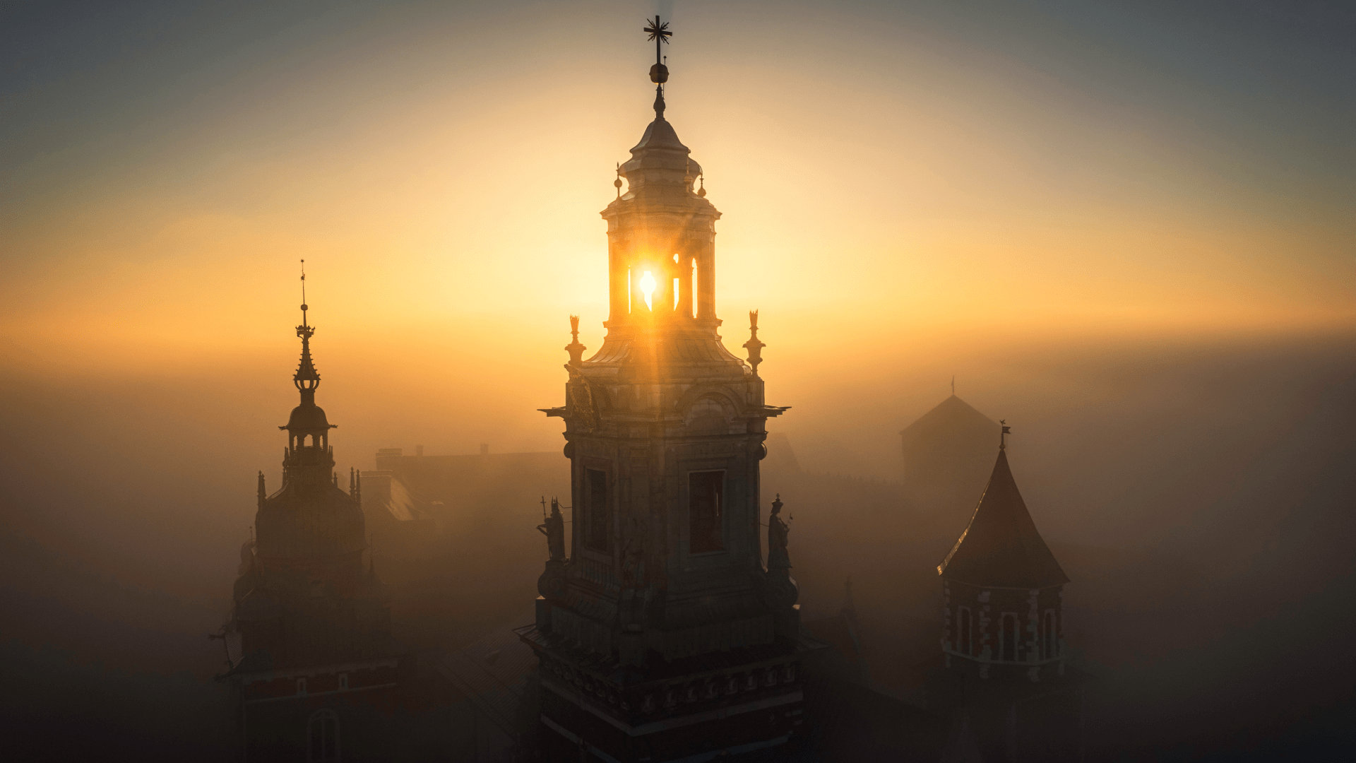 Krakow Old Town skyline at sunrise with church towers in silhouette.