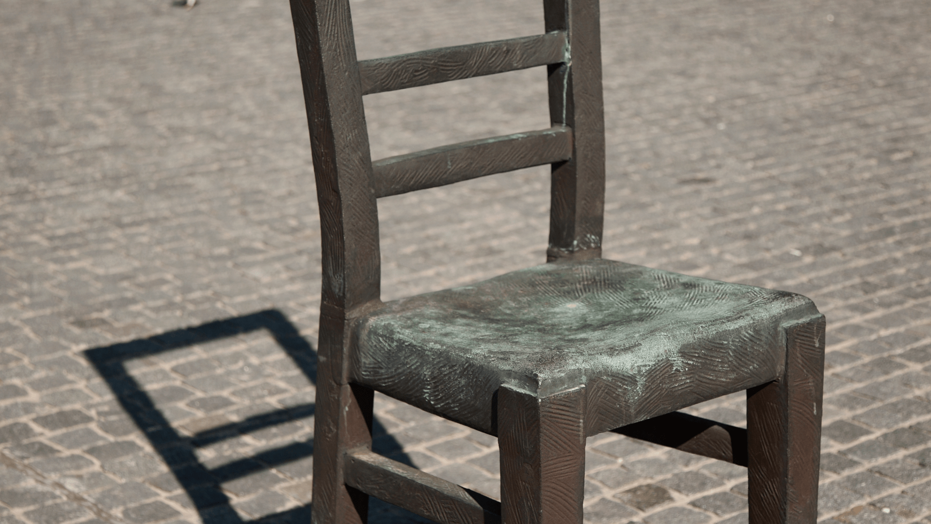 Weathered wooden chair sitting outside with grass and bushes behind