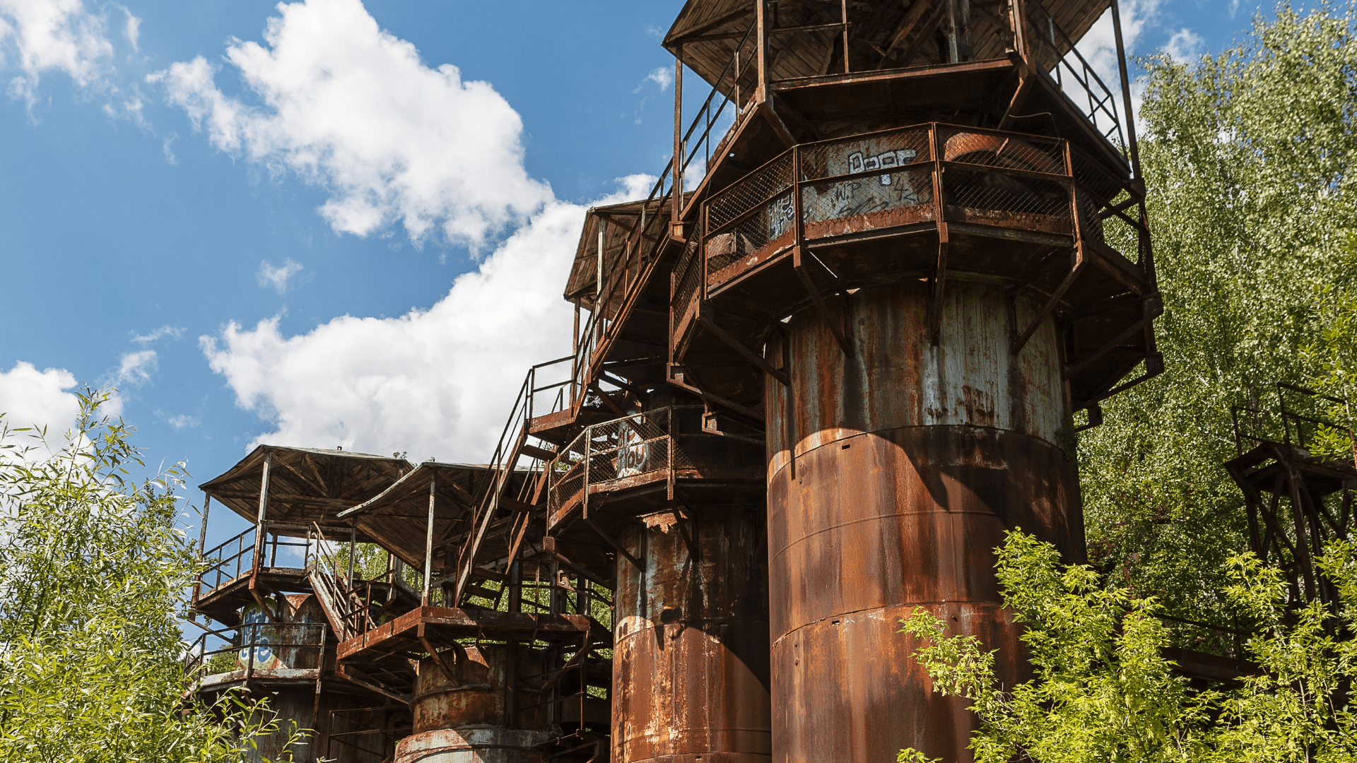 Rusted industrial towers and staircases against a blue sky