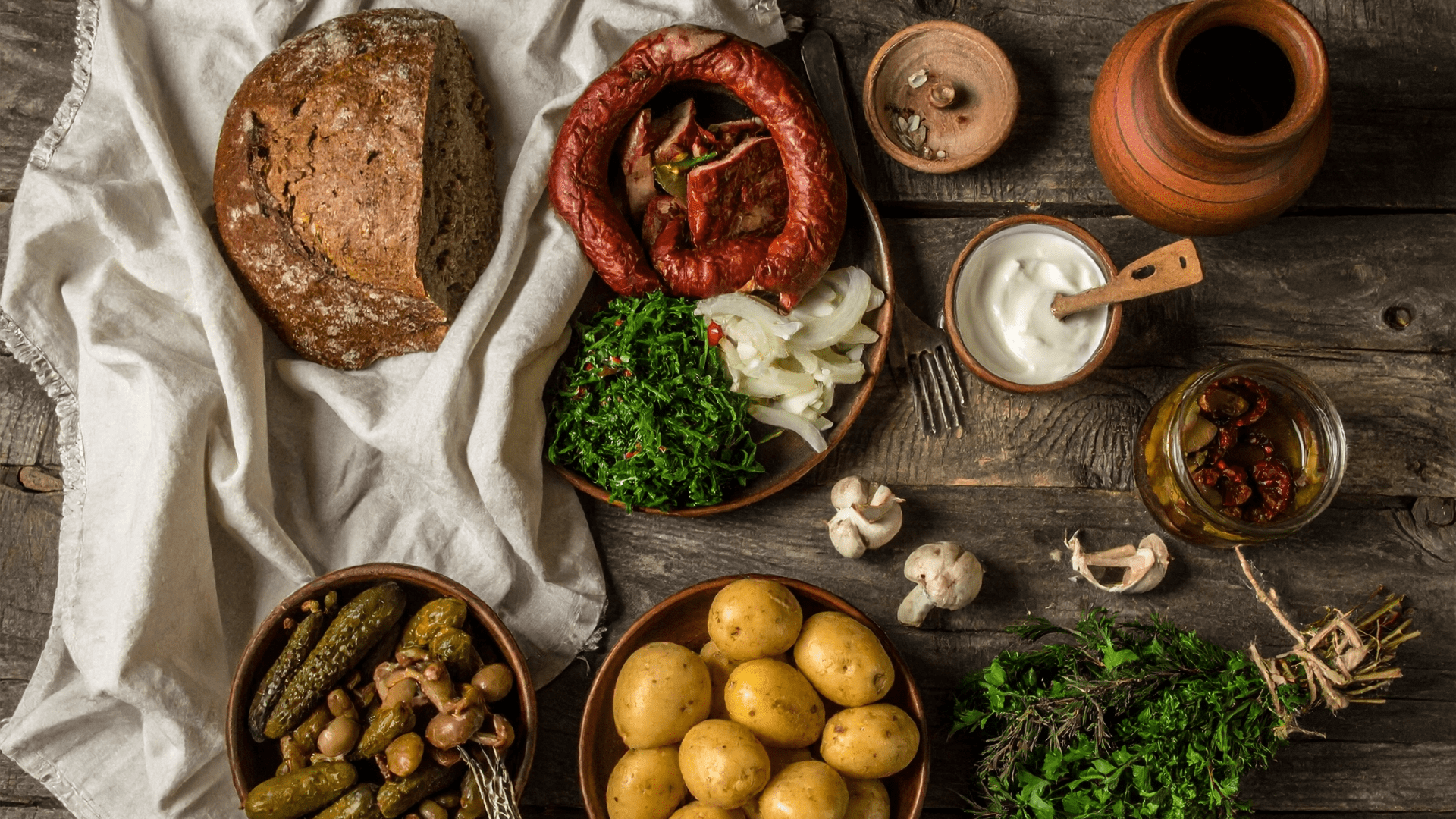 Rustic table with bread, herbs, grains, and traditional clay dishes