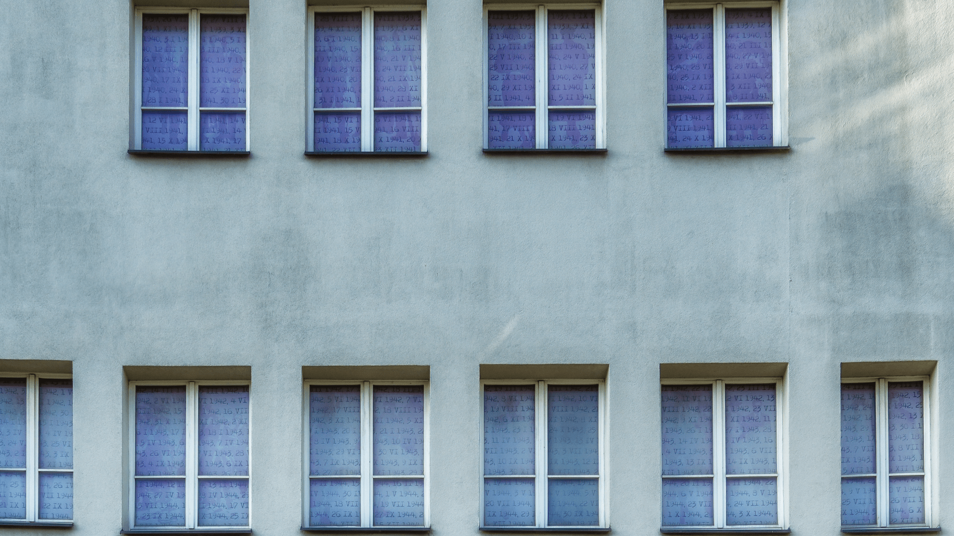 “Facade of a pale building with multiple square windows in rows