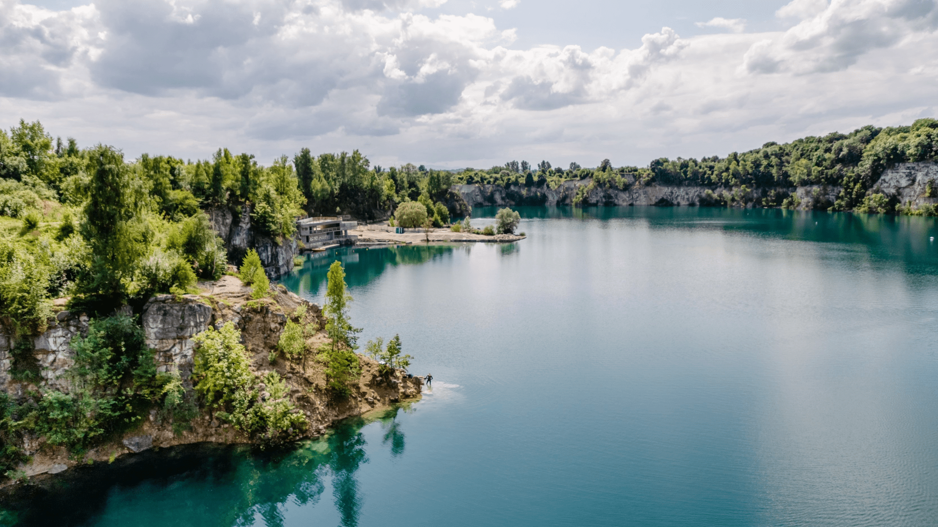 Scenic turquoise water lake bordered by lush green trees on a sunny day