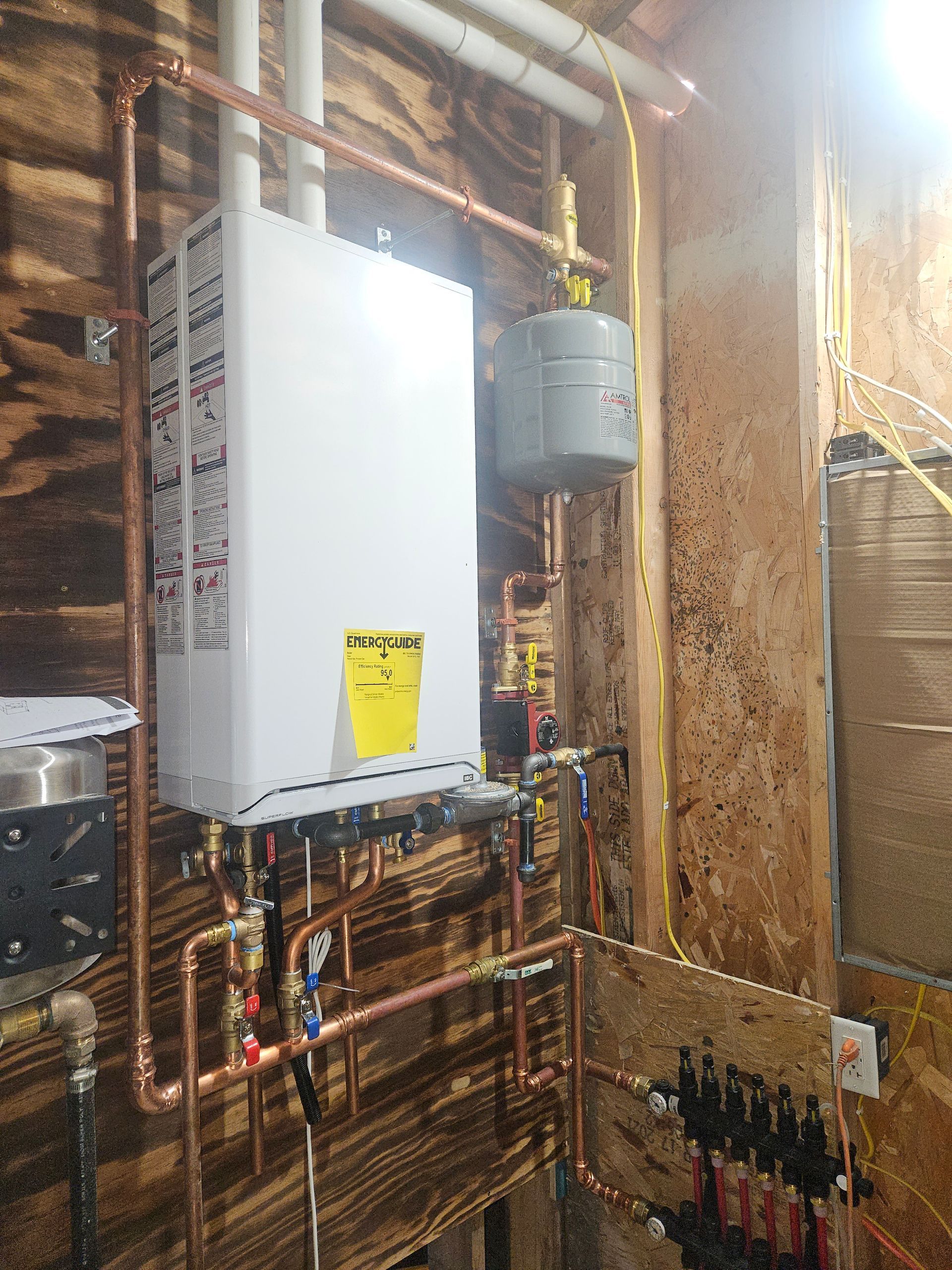 A water heater is installed in a room with copper pipes.