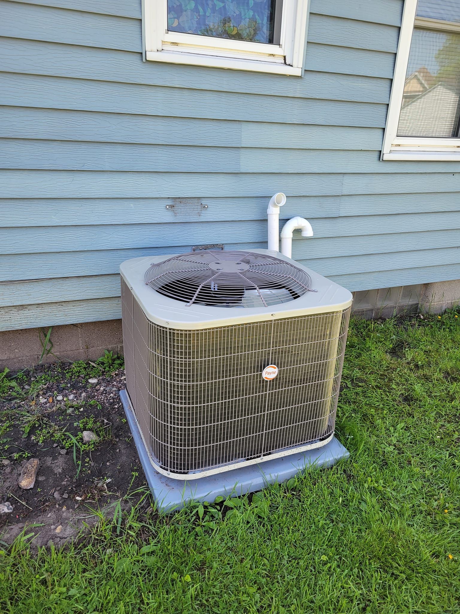 An air conditioner is sitting on the side of a house.