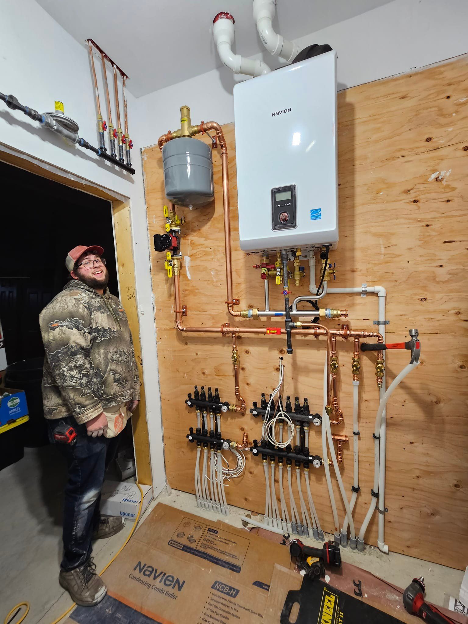 A man is standing in a room with a boiler on the wall.