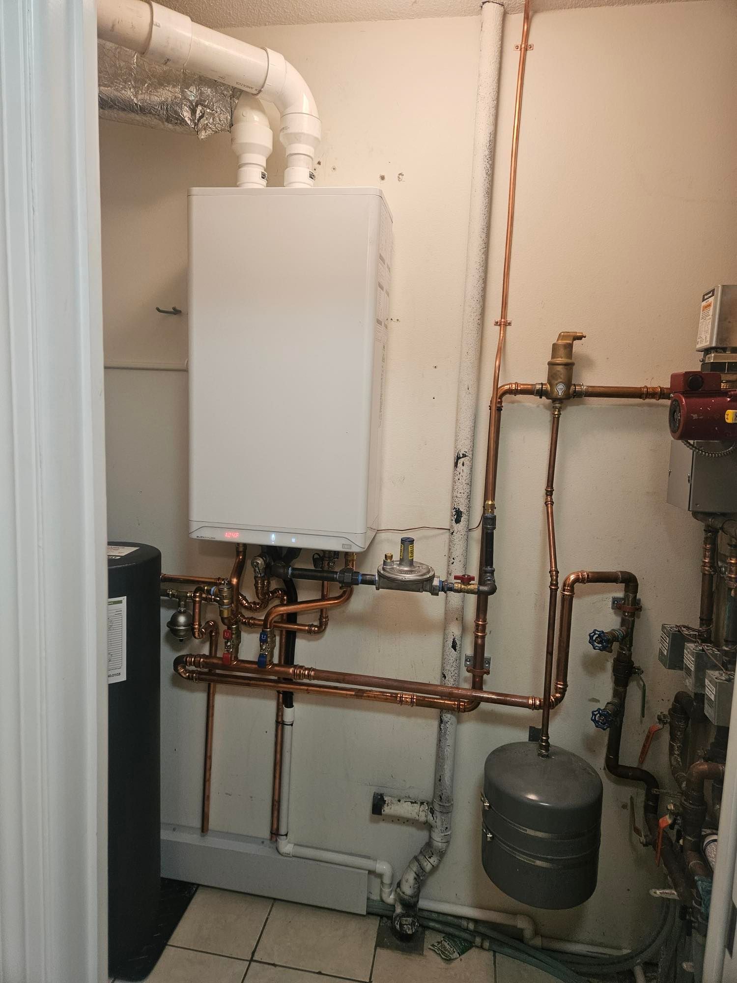 A room with a boiler and copper pipes on the wall.