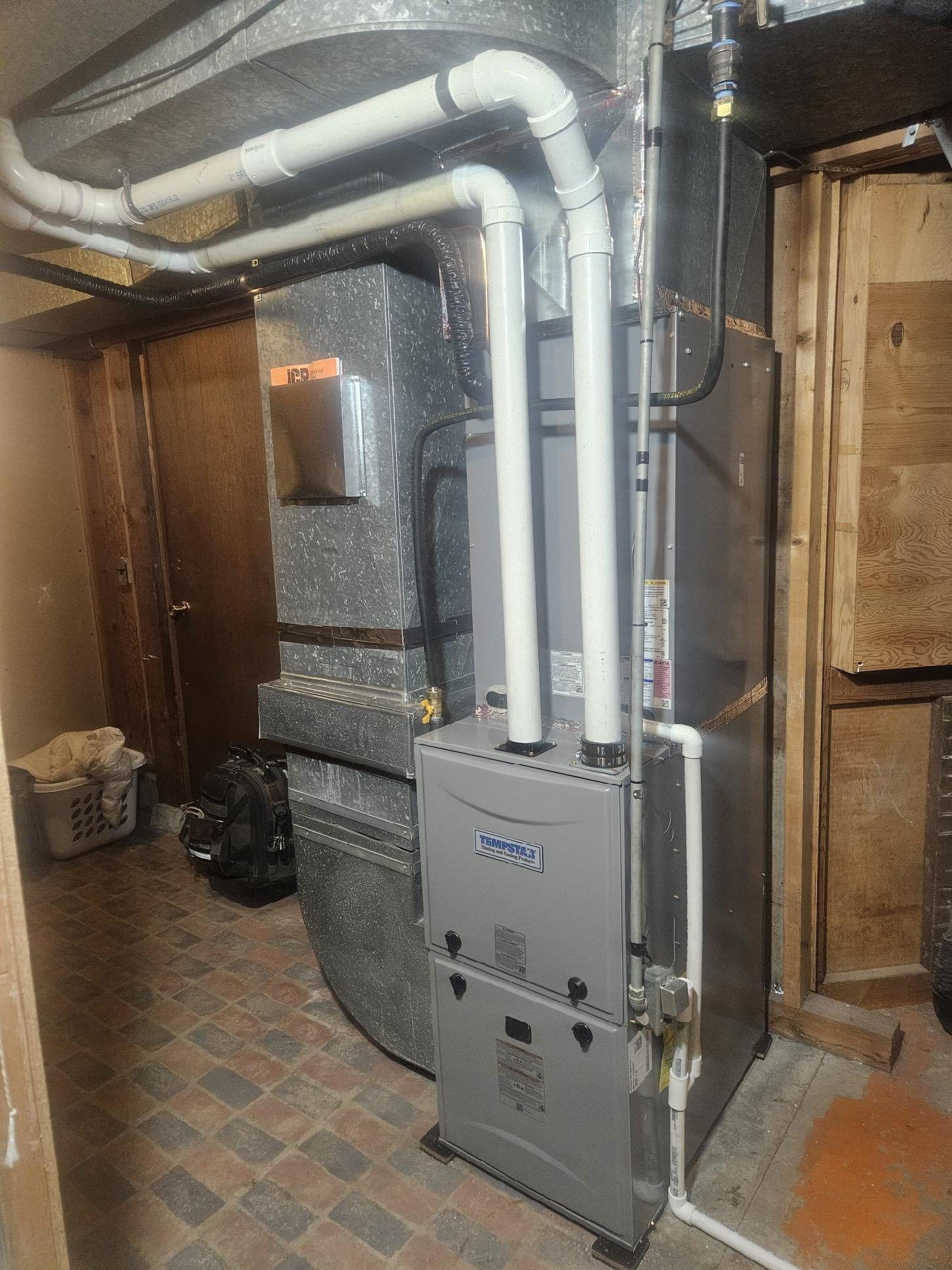 A furnace is sitting in the corner of a room in a basement.