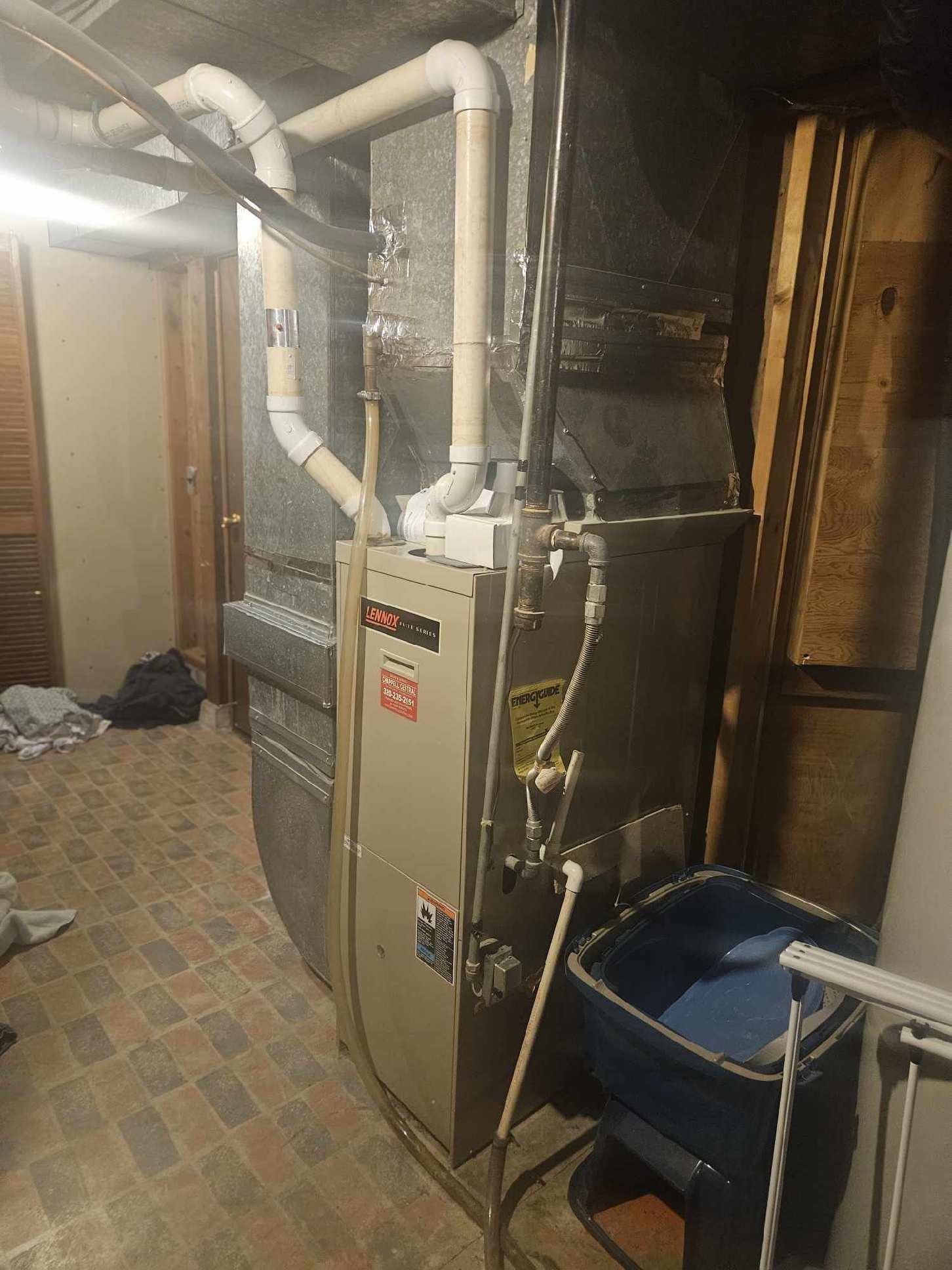 A furnace is sitting in a basement next to a water heater.