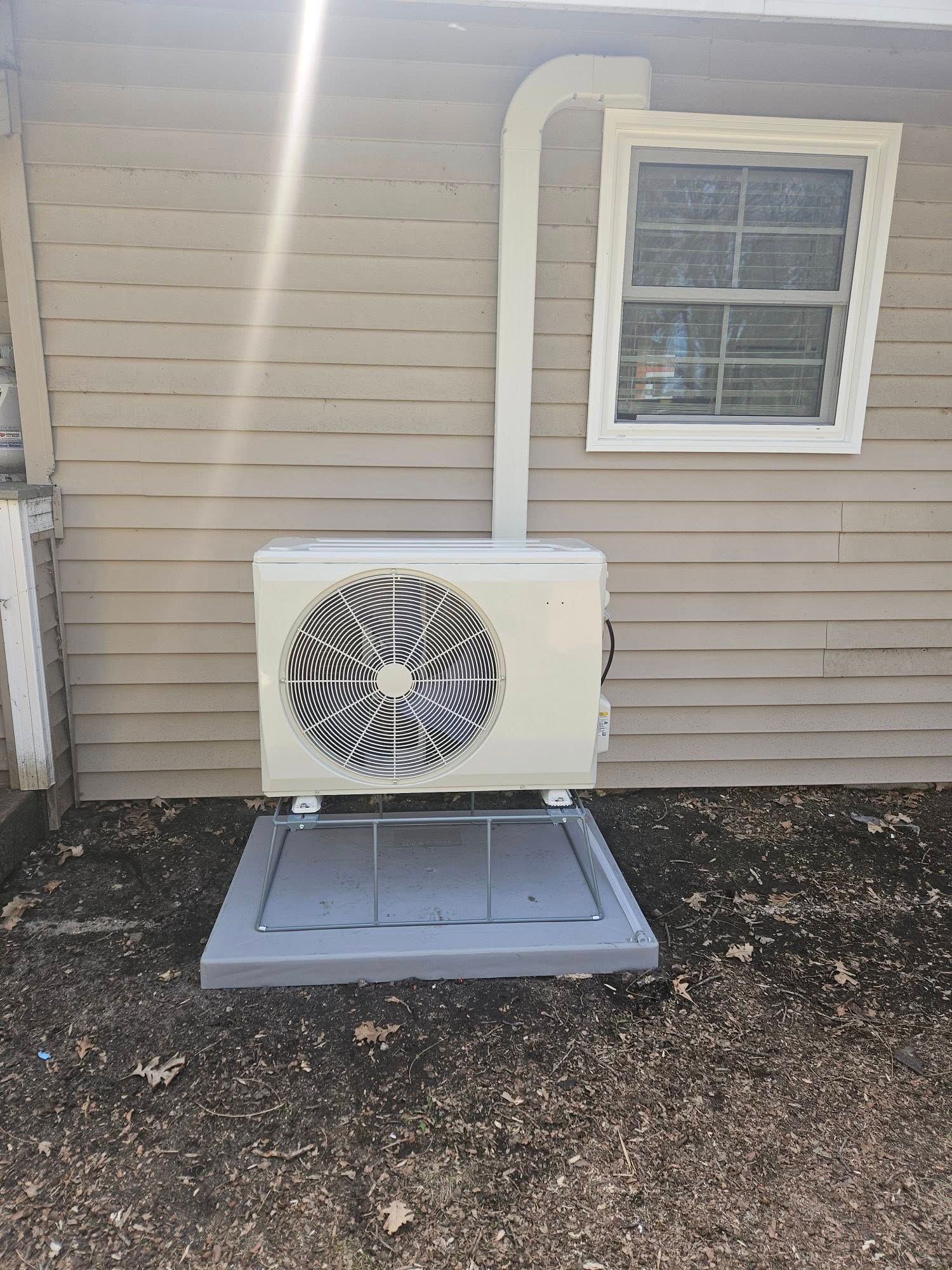 A white air conditioner is installed on the side of a house.