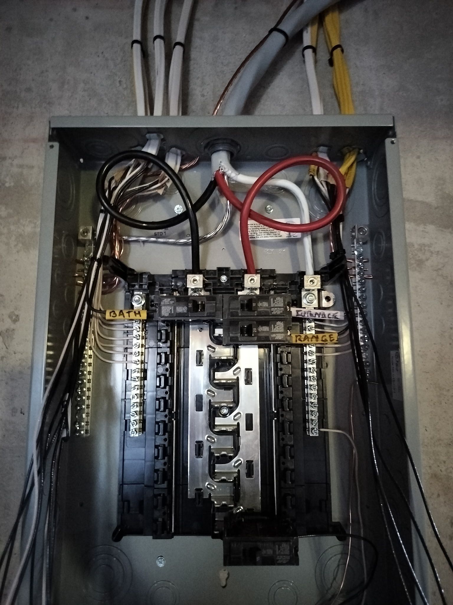 Open electrical breaker panel with exposed wiring and circuit breakers.