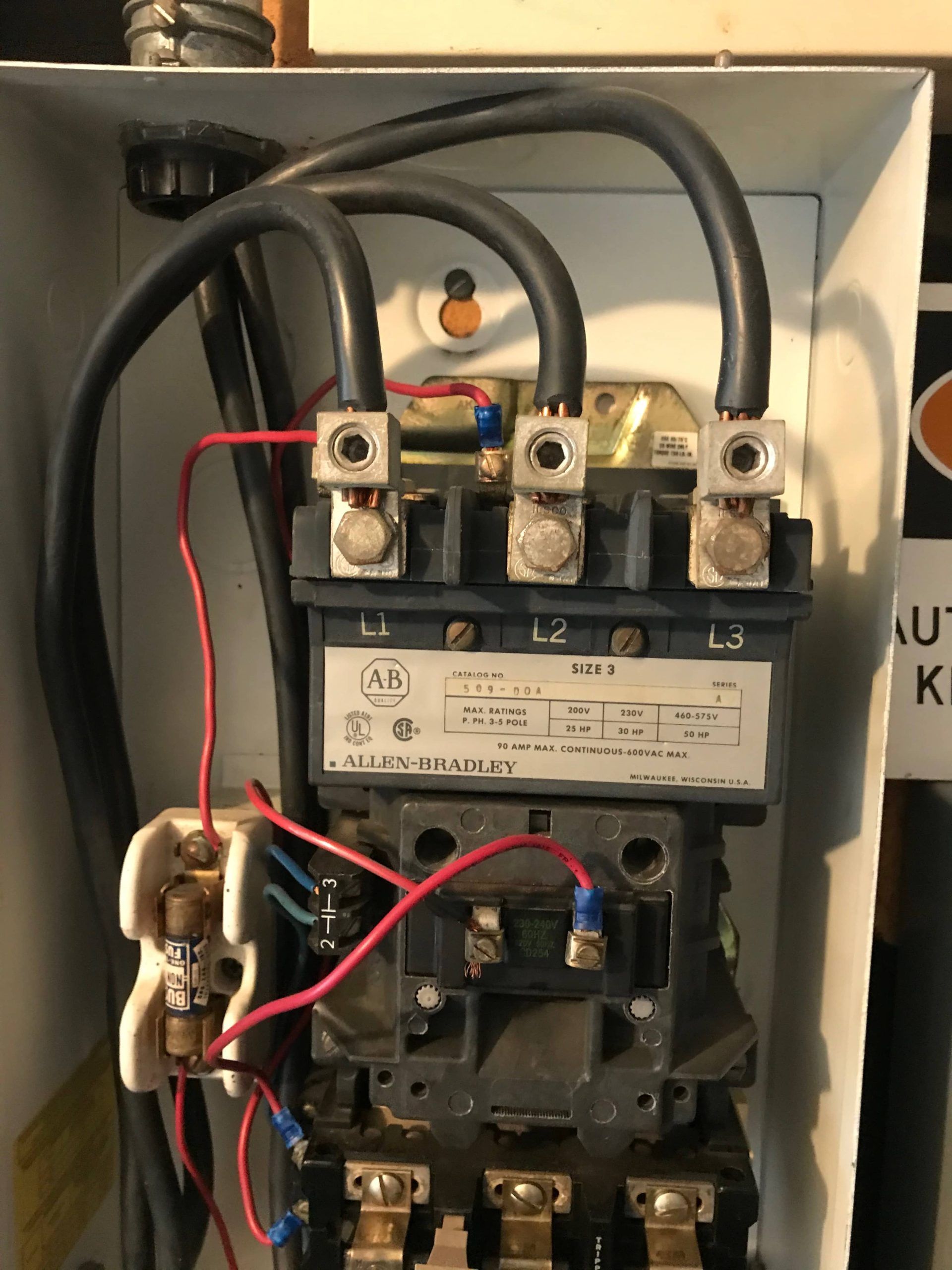 Open electrical panel with circuit breaker and red and black wires connected inside.