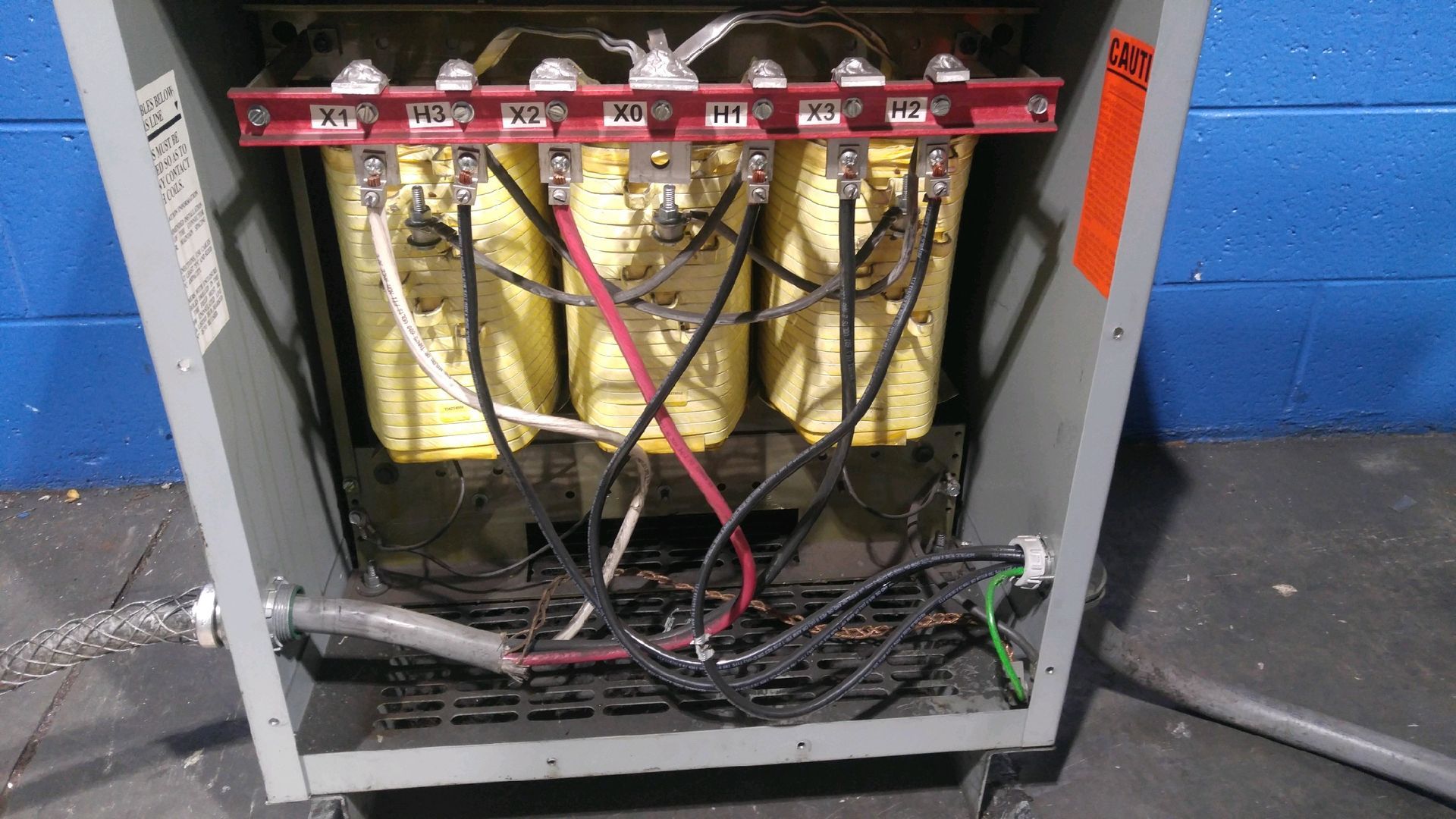 Open server cabinet with tangled cables and gold components inside, on a workshop floor.