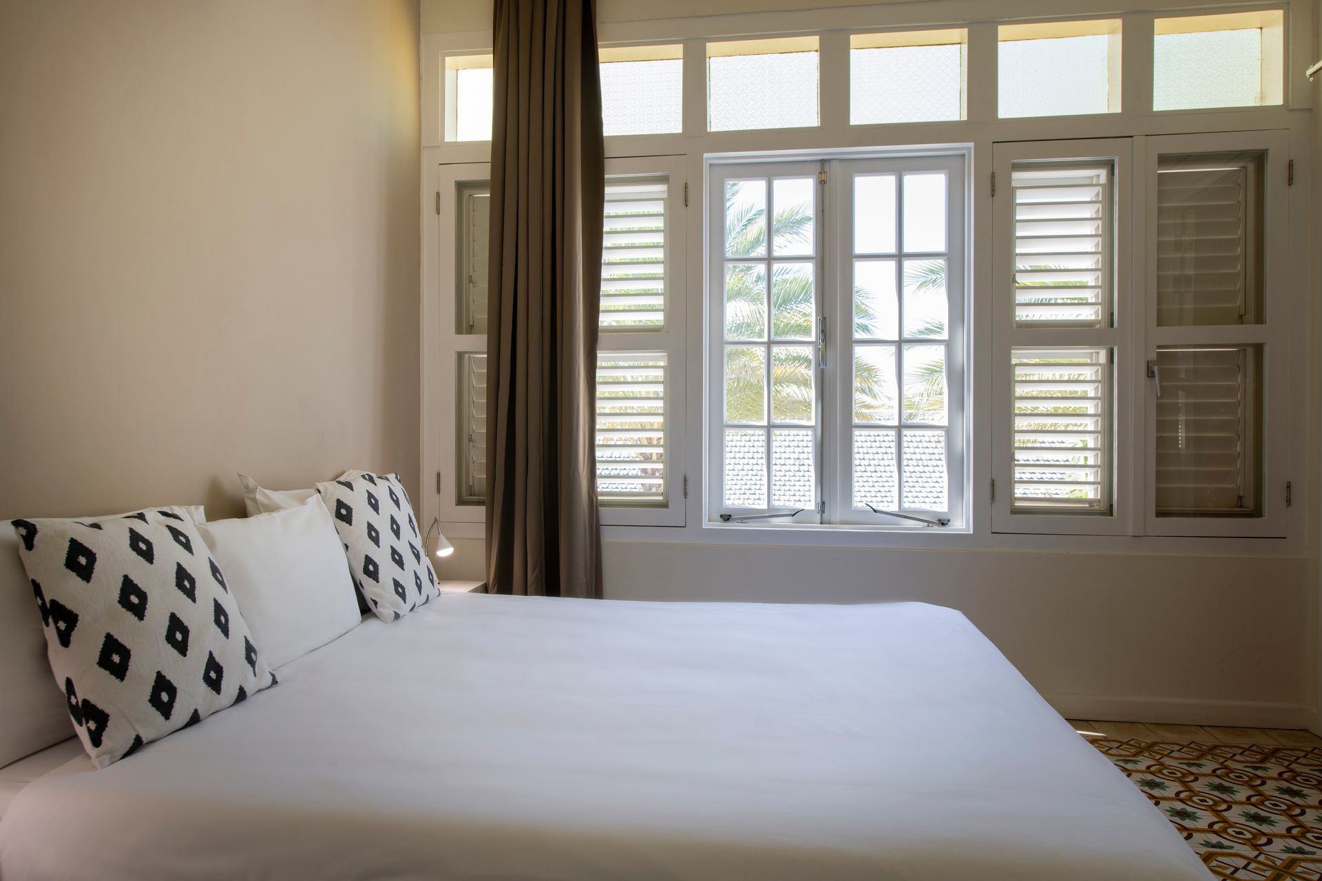 A bedroom with a bed and a window with shutters.