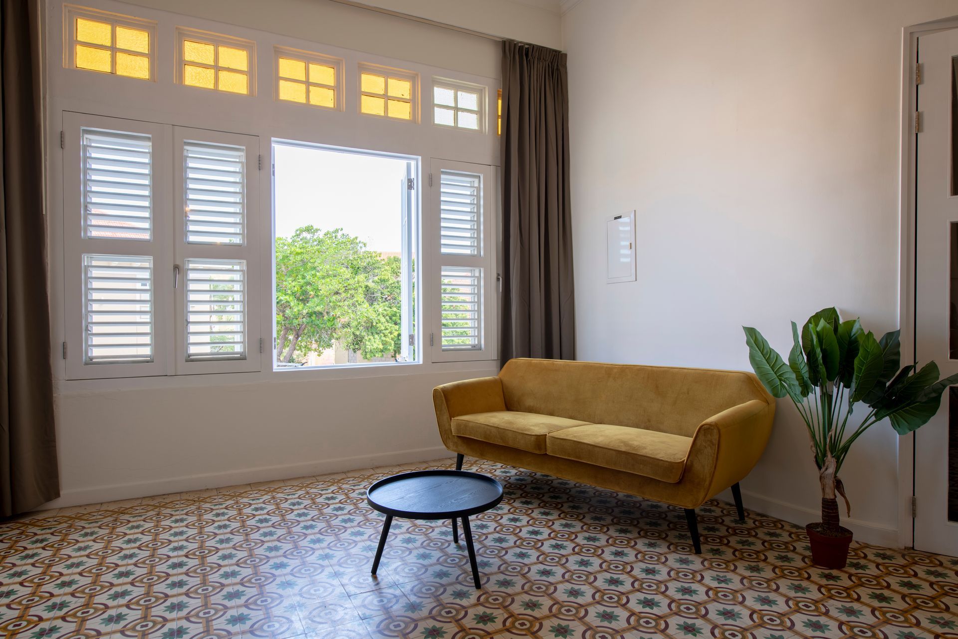 A living room with a yellow couch and a black coffee table. t Klooster Hotel Curacao