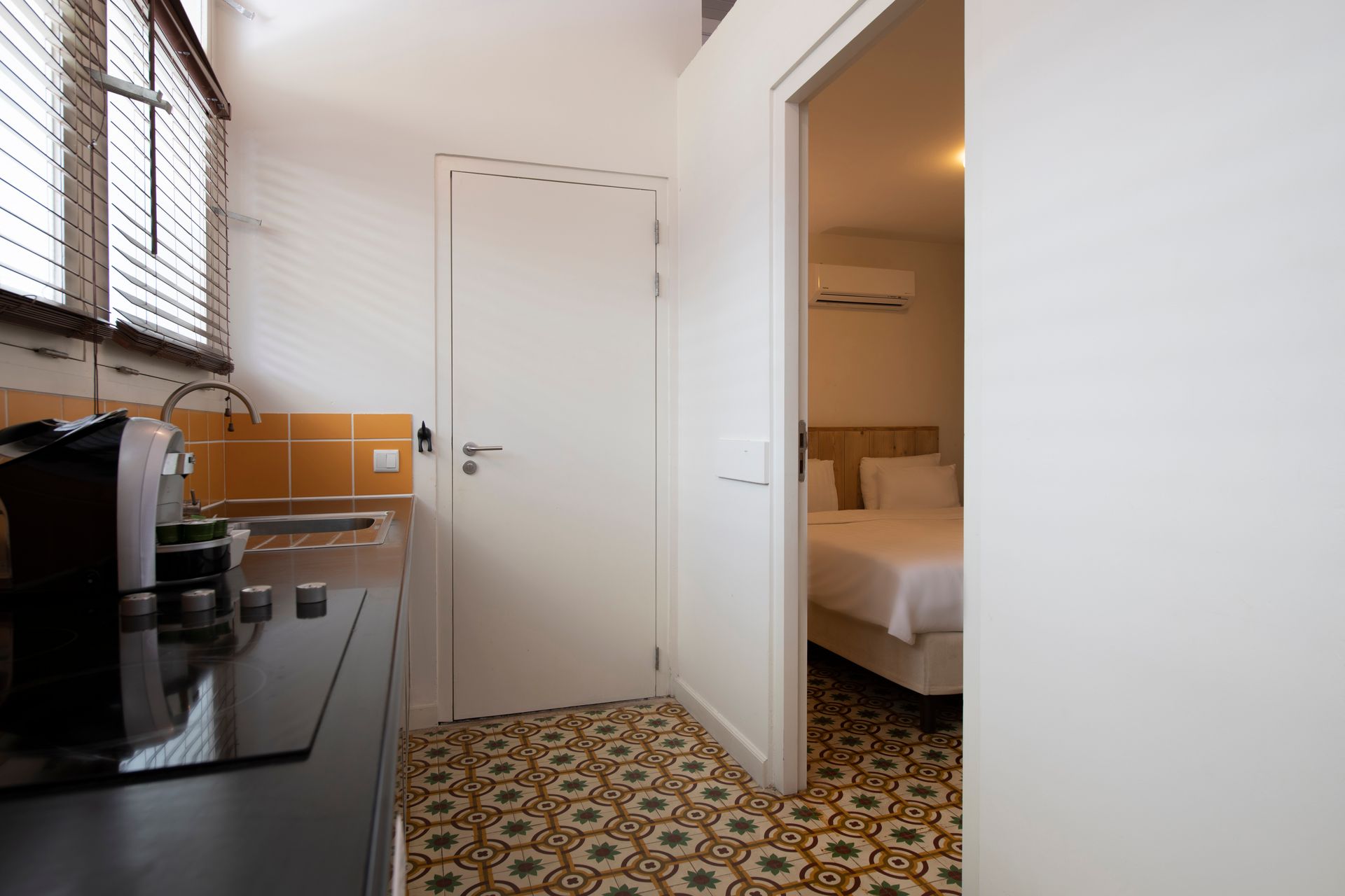 A kitchen with a stove top oven and a bed in the background.