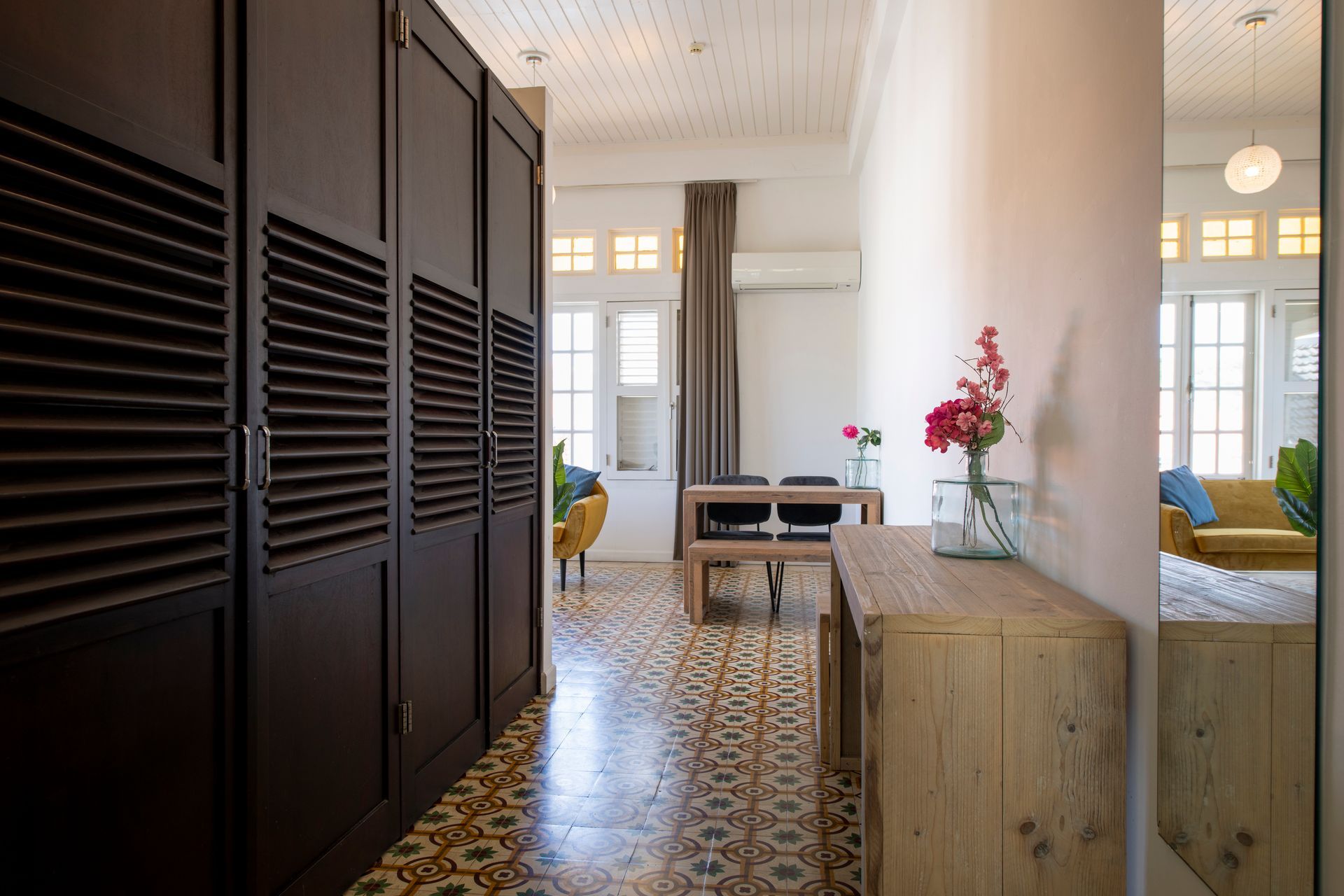 A hallway in a house with a wooden table and a vase of flowers on it.