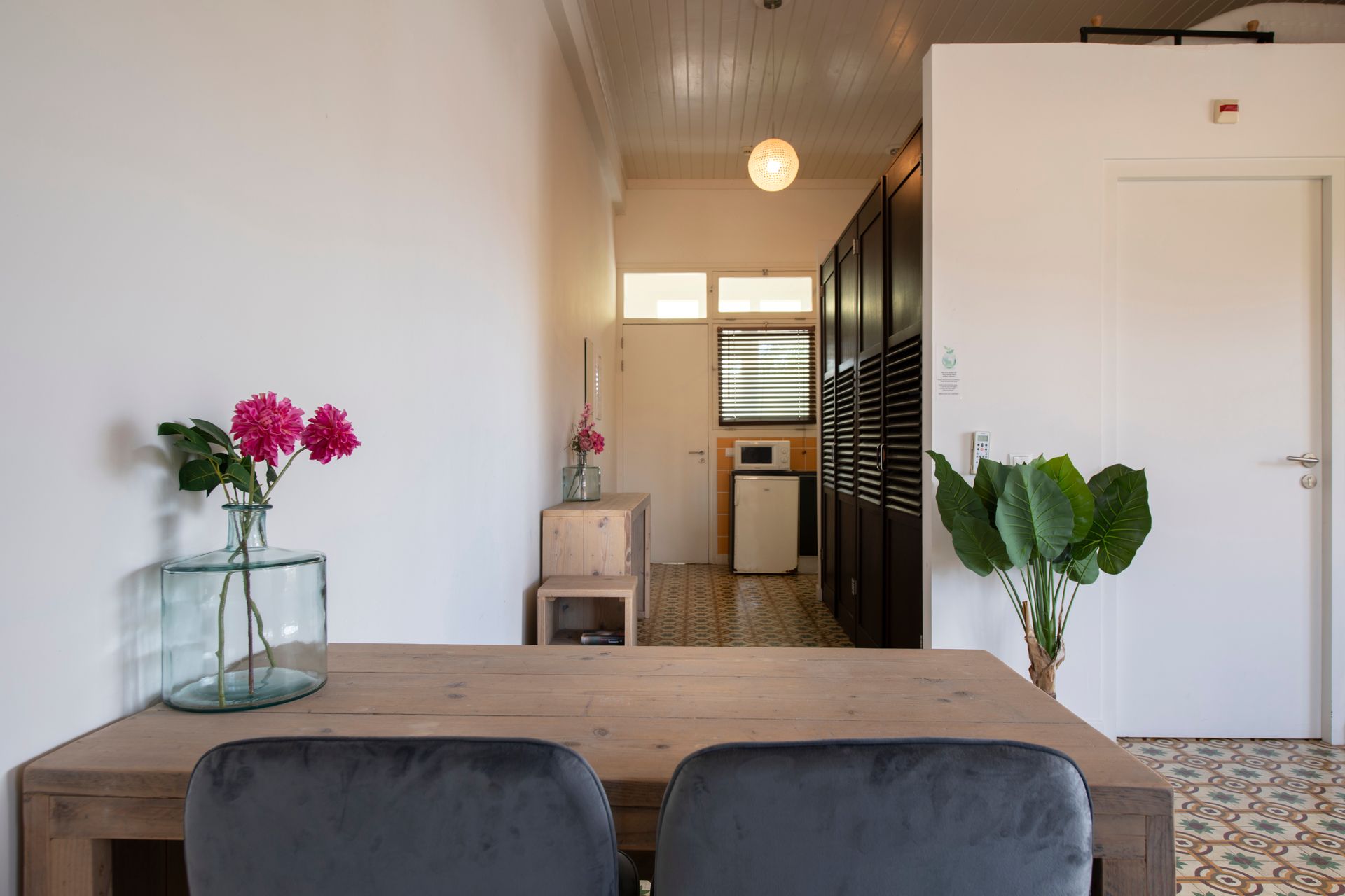 A dining room table with two chairs and a vase of flowers on it.