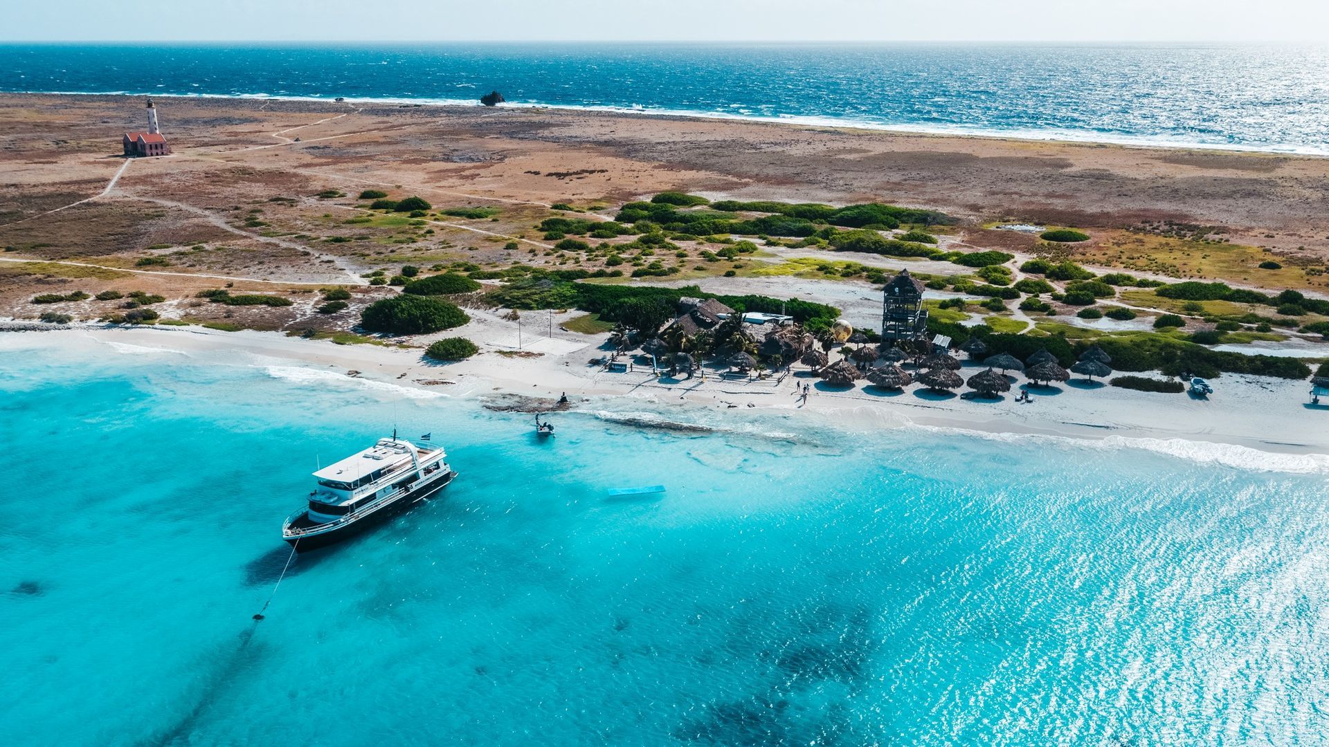 An aerial view of a small island in the middle of the ocean with a boat in the water.