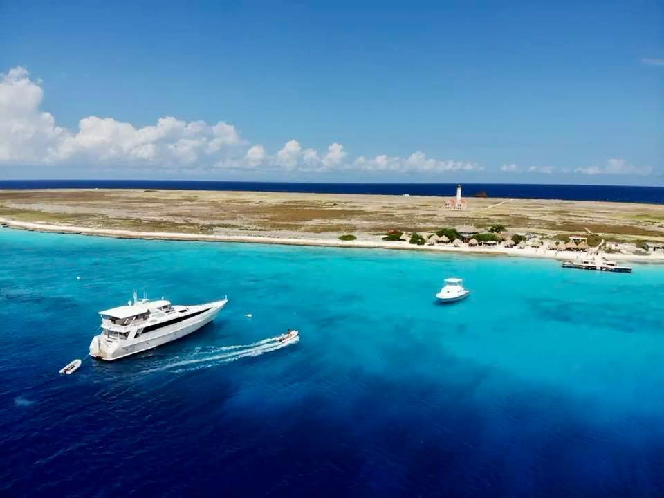 An aerial view of a yacht in the ocean near a small island.