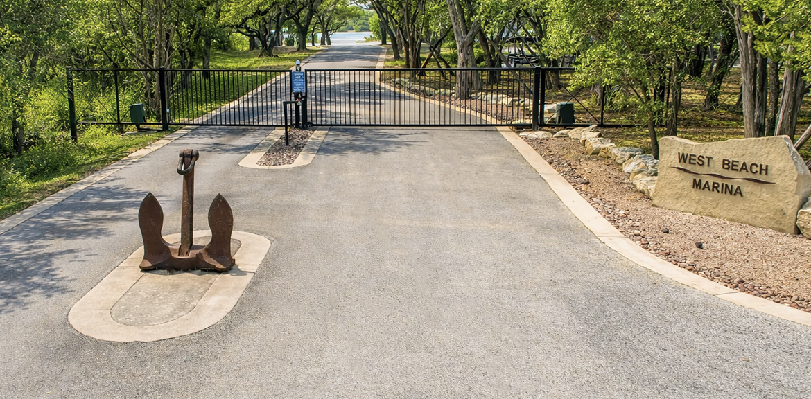 Entrance to First Beach Marina with a decorative anchor, gated driveway, and sign.